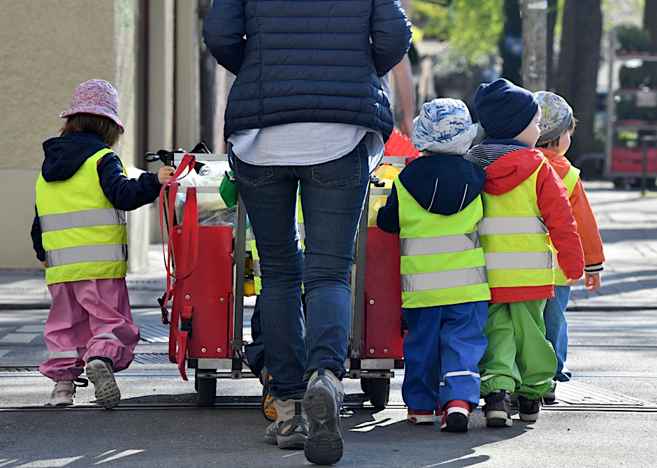 ARCHIV - Ein Betreuerin läuft mit mehreren Kleinkindern durch München.  