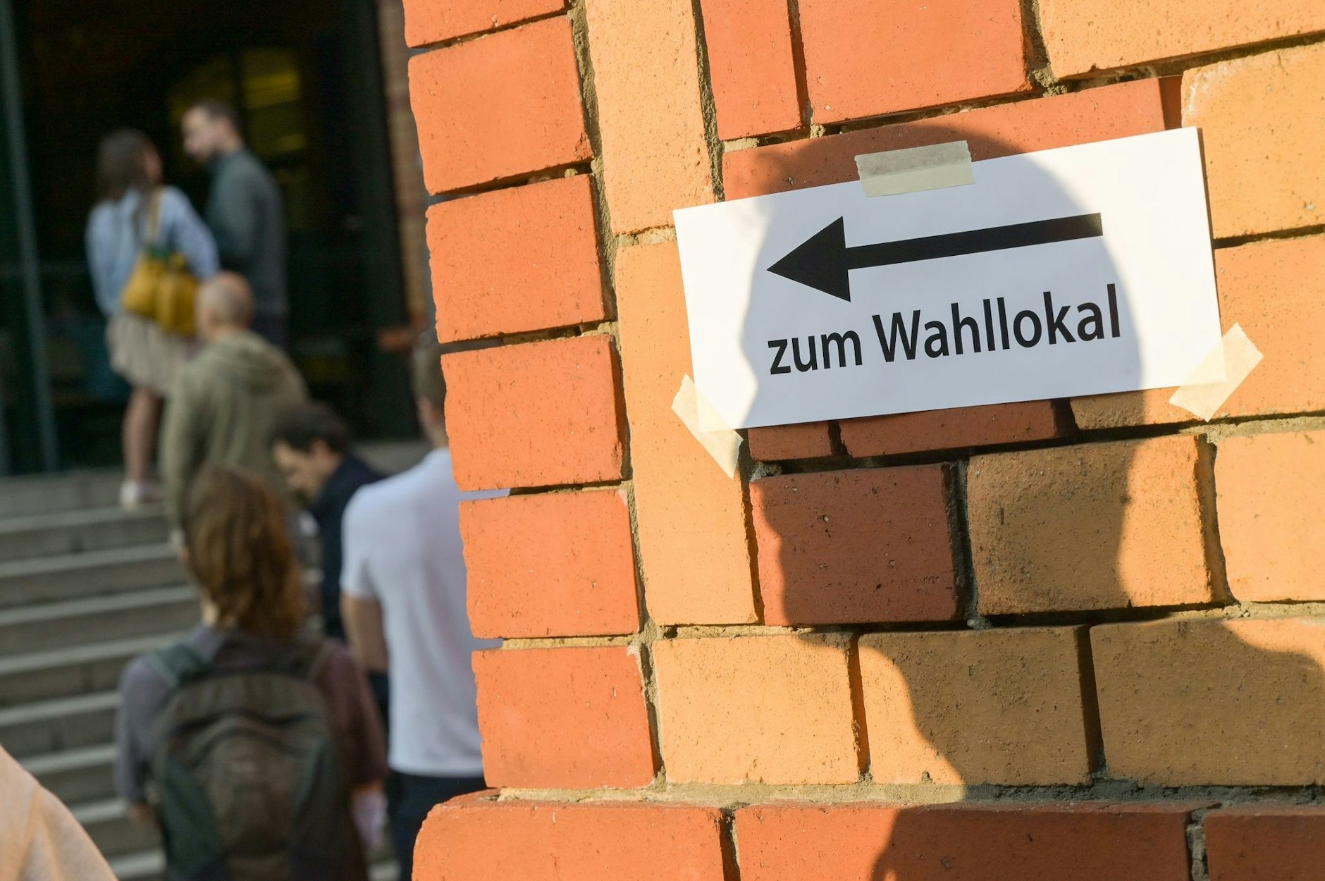 ARCHIV - Wählerinnen und Wähler stehen kurz vor der Schließung der Wahllokale vor einem Wahllokal in Berlin.  