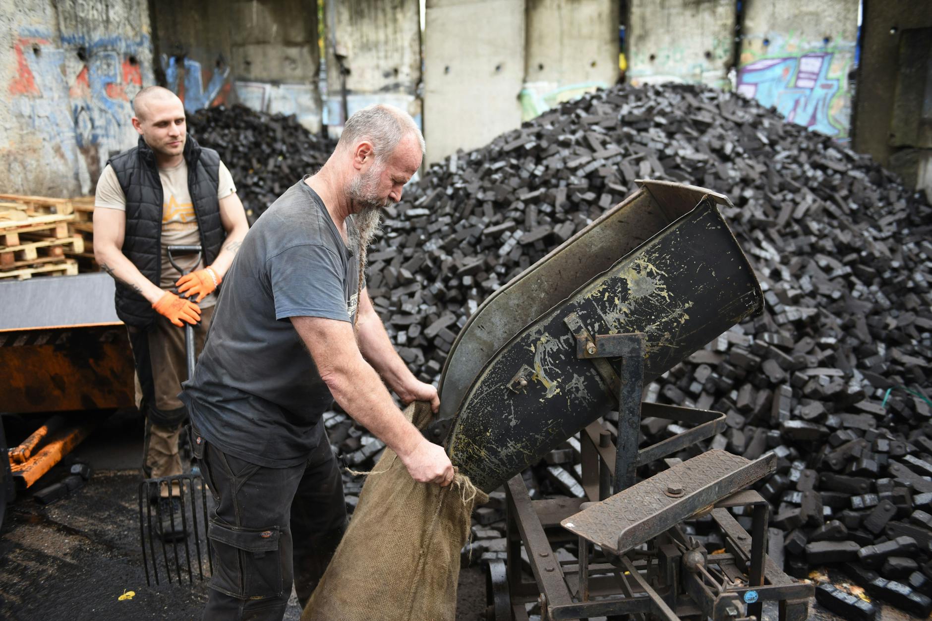 Der Kohlenhändler Arnd Teiche füllt auf seinem Kohlenplatz in Berlin-Prenzlauer Berg Schüttkohle in einen Sack.