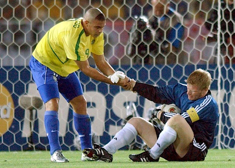 ARCHIV - Der brasilianische Stürmer Ronaldo hilft im WM-Finale 2002 dem DFB-Torhüter Oliver Kahn auf die Beine.  