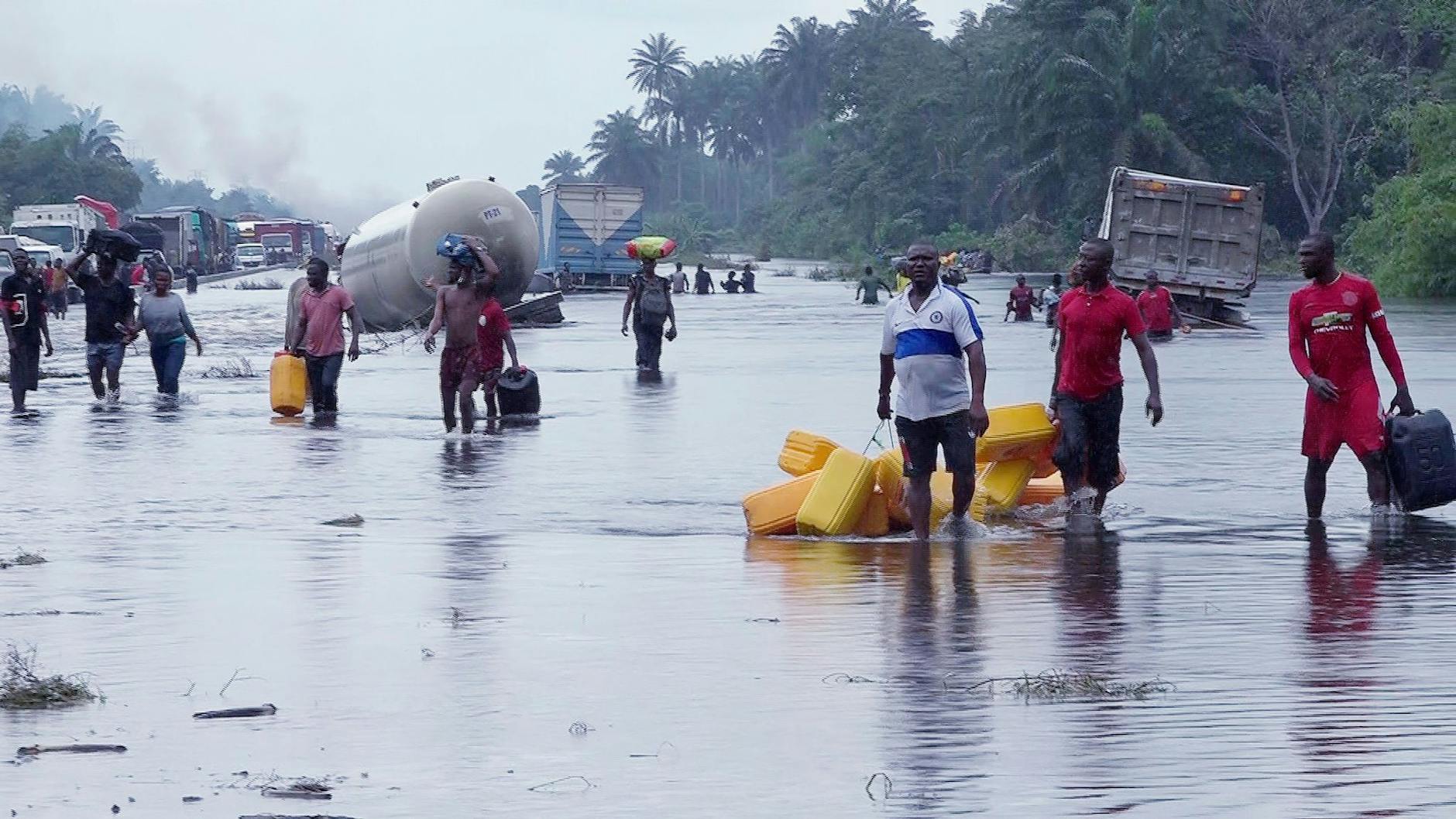 Menschen im nigerianischen Bayelsa waten durch überflutete Straßen.  