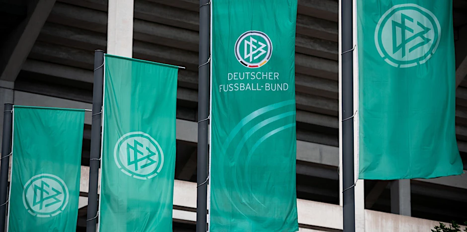 Fahnen mit dem Logo des Deutschen Fussball-Bund (DFB) wehen vor einem Stadion.   - Nutzung nur nach schriftlicher Vereinbarung mit der dpa