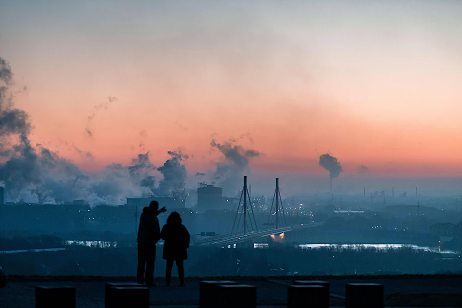 <strong>Zwei Menschen stehen bei Sonnenaufgang auf der Halde Rheinpreußen in Moers und gucken in Richtung des Industriegebiet von Thyssen-Krupp.</strong>