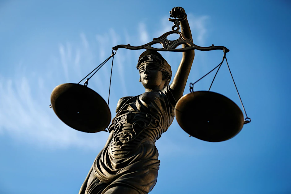 Eine Statue der Justitia hält eine Waage in ihrer Hand.