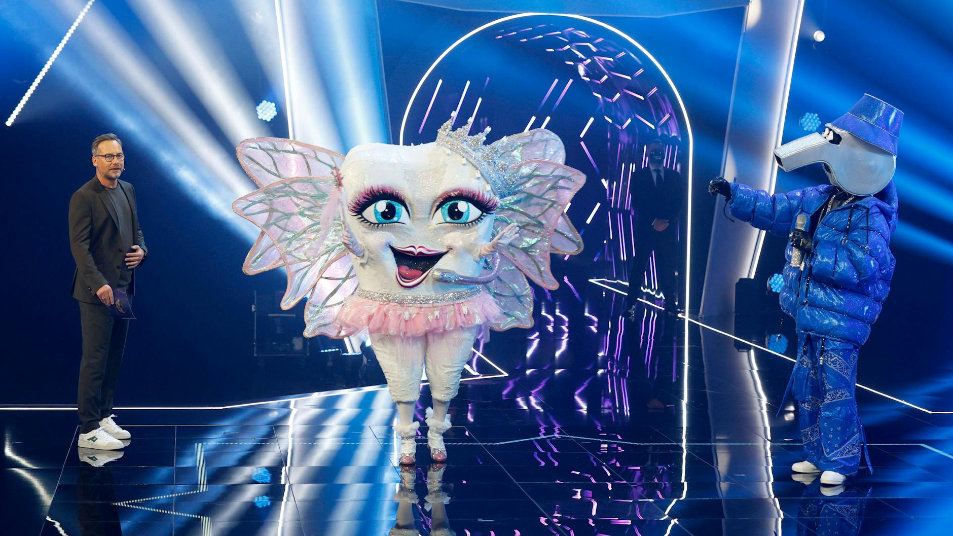 Die Zahnfee mit der Pfeife und Moderator Matthias Opdenhövel auf der Masked Singer-Bühne.