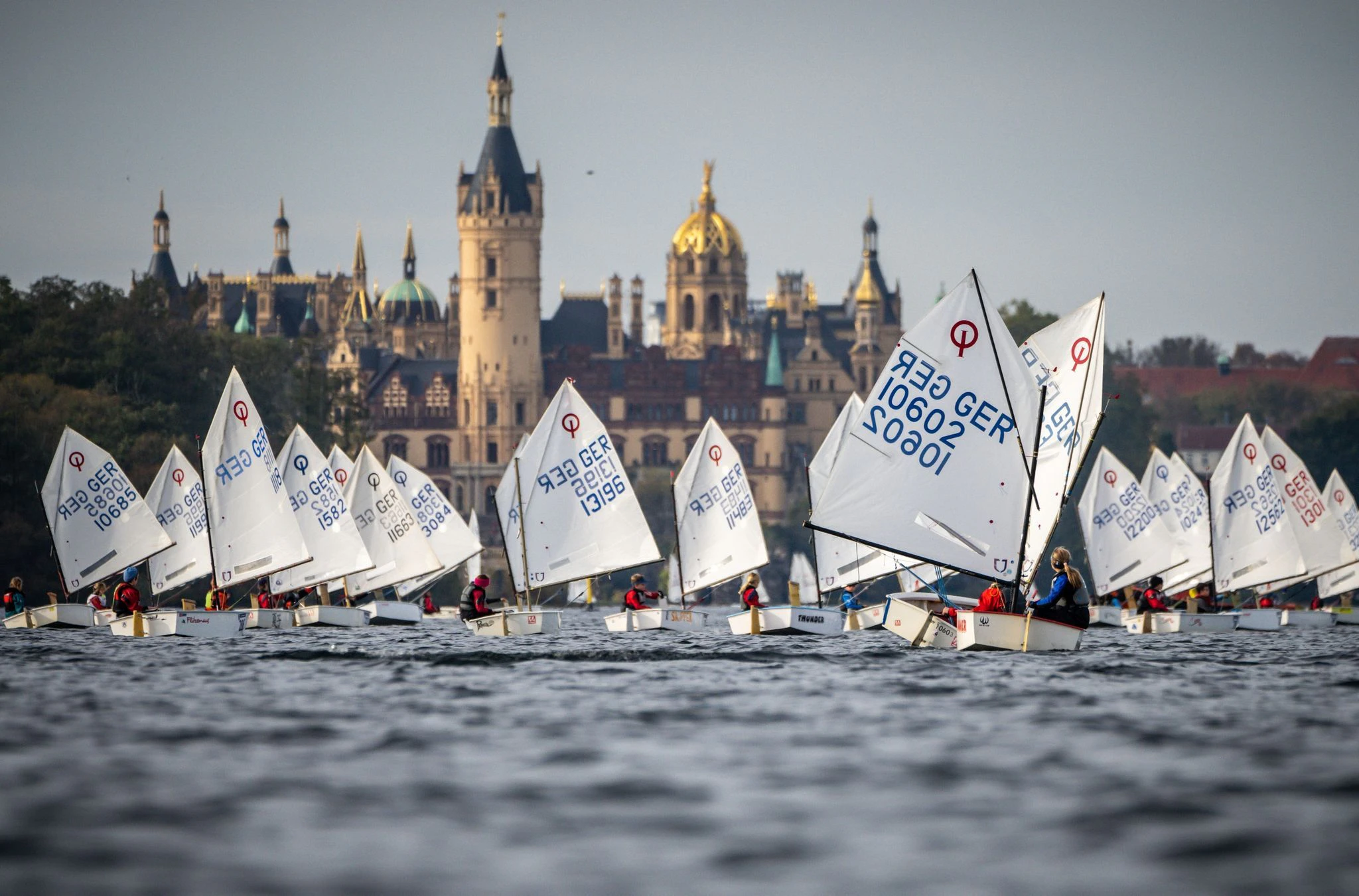 Segler der Nachwuchs-Bootsklasse "Optimist" sind beim Herbstpokal auf dem Schweriner See vor dem Schweriner Schloss unterwegs. Über 400 Seglerrinnen und Segler in verschiedenen Klassen sind beim Saison Abschluss auf dem Wasser.  