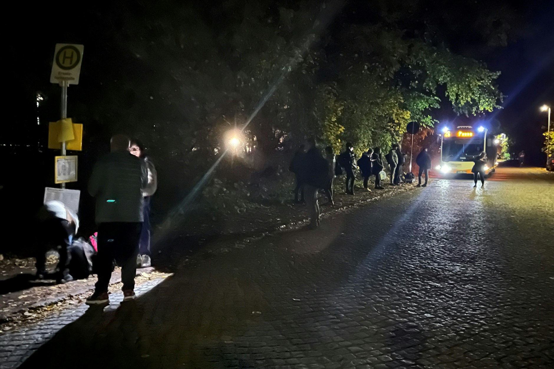 Schienenersatzverkehr auf der Regionalbahnlinie RB26 östlich von Berlin. Am Bahnhof Müncheberg warten Fahrgäste im Dunkeln auf den Bus nach Strausberg. Mit Handylampen versuchen sie sich zu informieren.