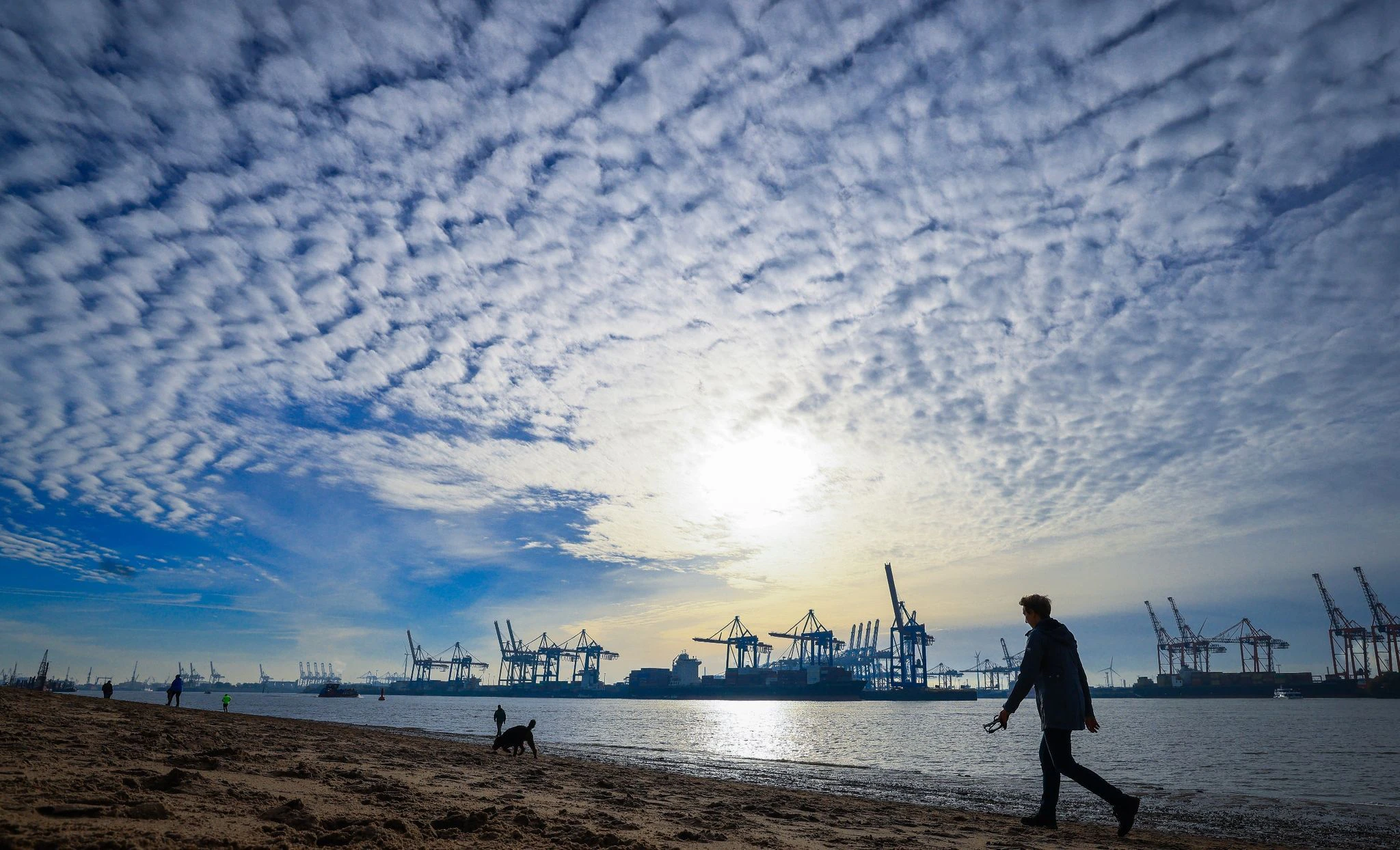 dpatopbilder - Das sonnige Herbstwetter läd Spaziergänger am Strand von Övelgönne an der Elbe zu einer gemütlichen Runde vor der Silhouette des Hamburger Hafens ein.  