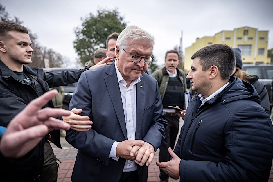 Bundespräsident Frank-Walter Steinmeier (M.) spricht mit Ratan Achmedow, Bürgermeister der Stadt Korjukiwka – in diesem Moment ertönt Luftalarm, und Sicherheitskräfte weisen den Weg in den Luftschutzbunker.