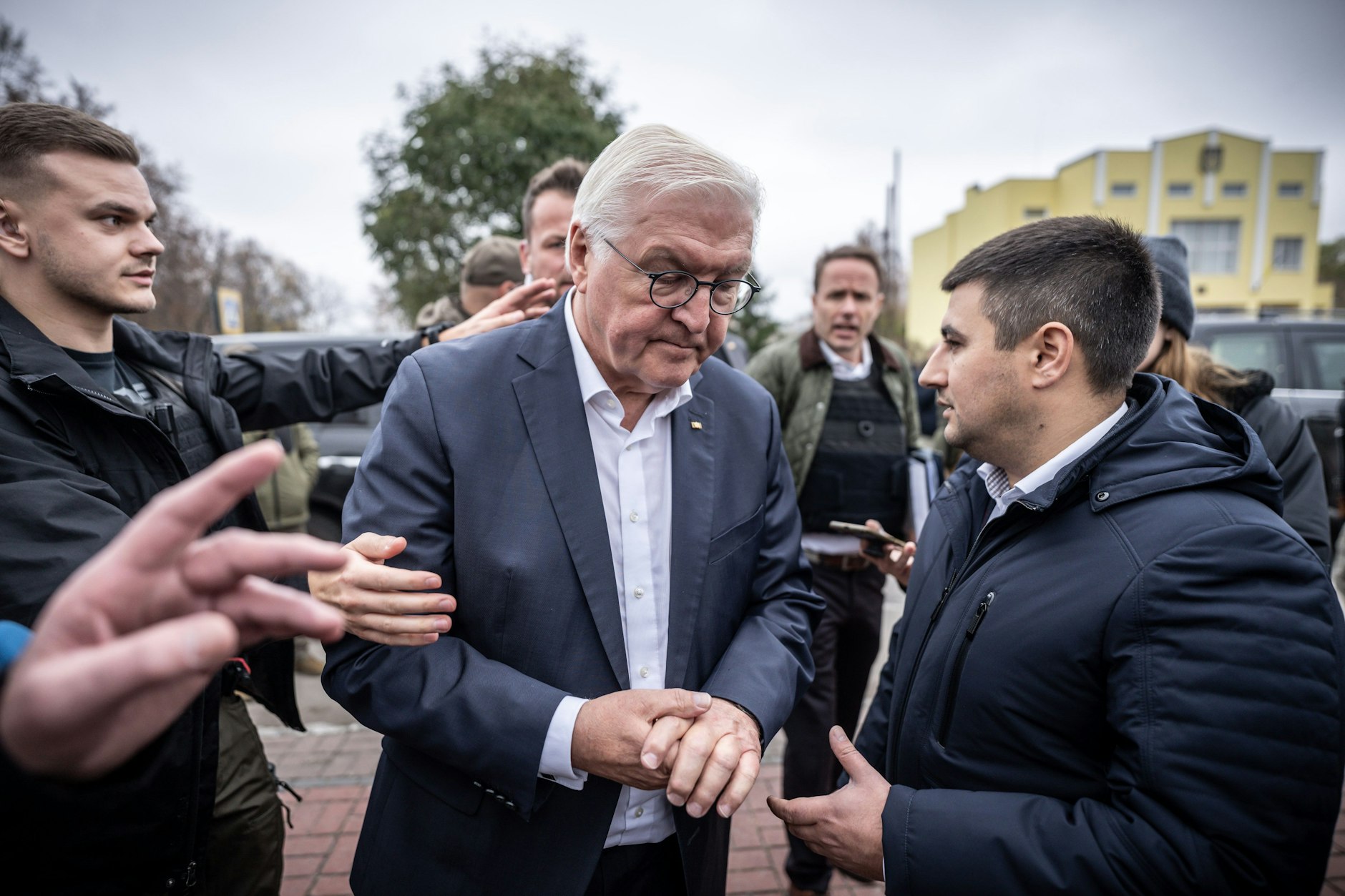 Bundespräsident Frank-Walter Steinmeier (M.) spricht mit Ratan Achmedow, Bürgermeister der Stadt Korjukiwka – in diesem Moment ertönt Luftalarm, und Sicherheitskräfte weisen den Weg in den Luftschutzbunker.