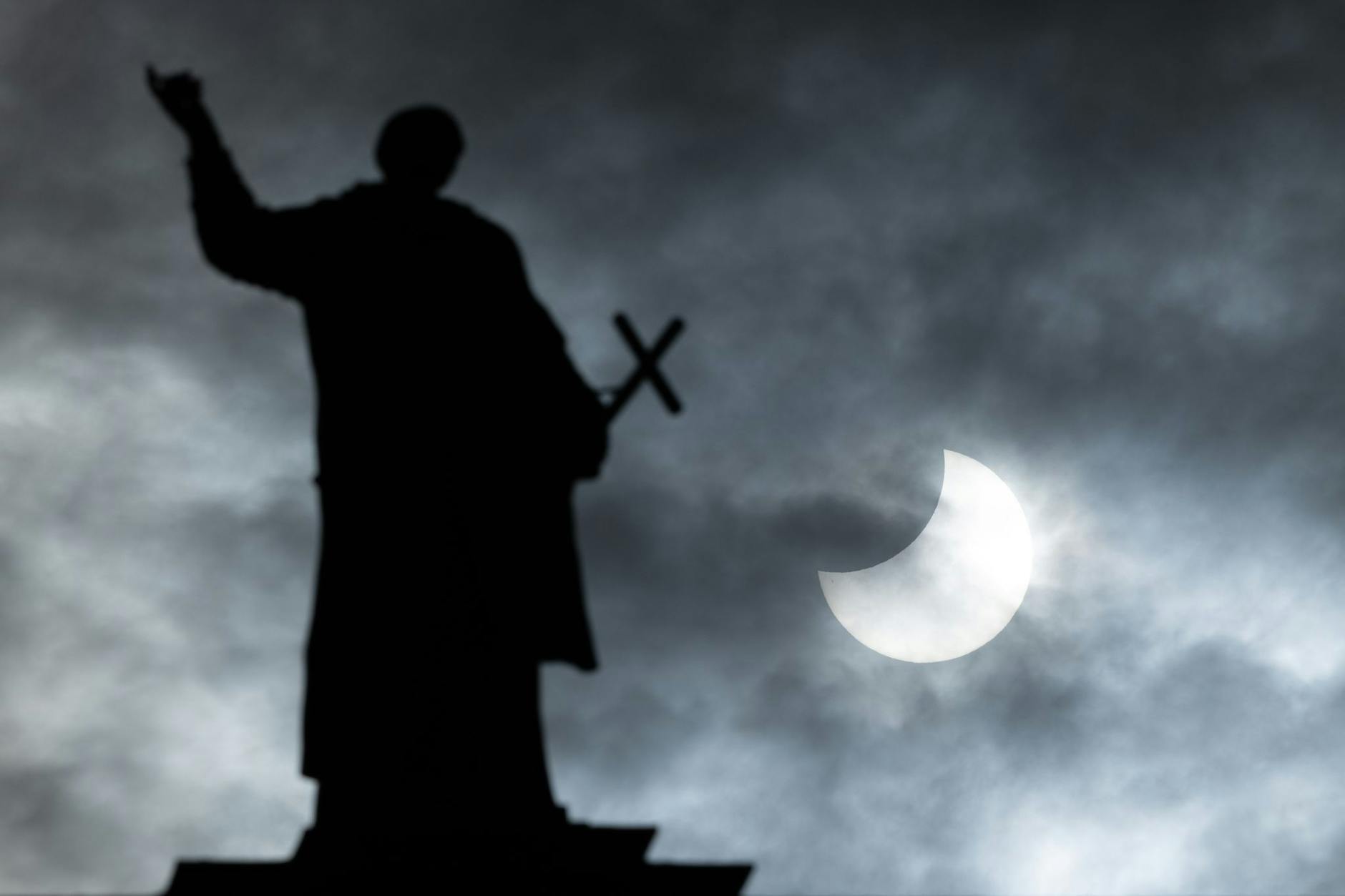 dpatopbilder - Bei einer partiellen Sonnenfinsternis wird die Sonne teilweise vom Mond verdeckt. Im Vordergrund ist eine Mattielli-Statue auf der Katholischen Hofkirche in Dresden zu sehen.
