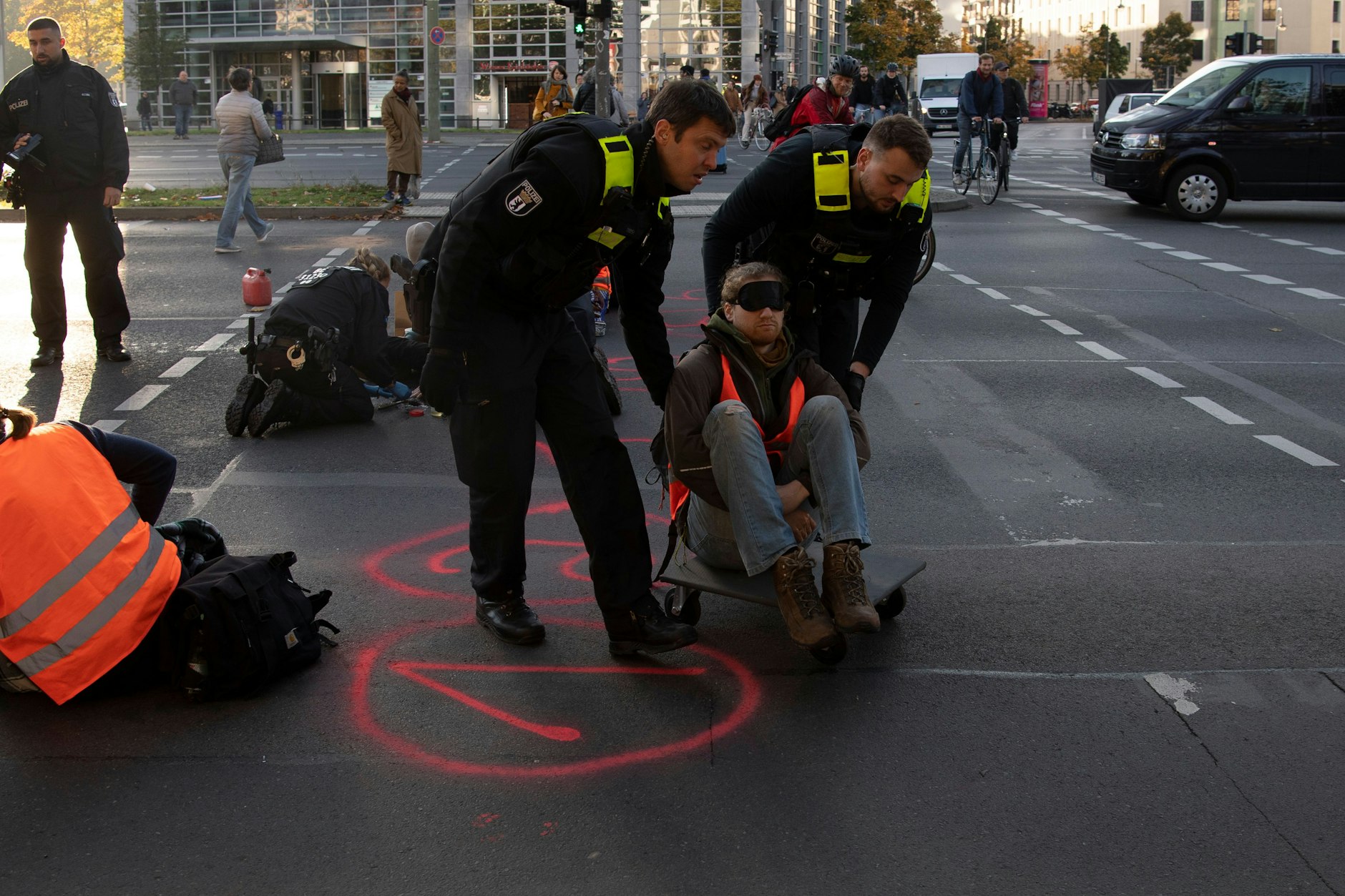 Ein Aktivist mit Augenbinde wird von der Polizei von der Kreuzung abgeführt.