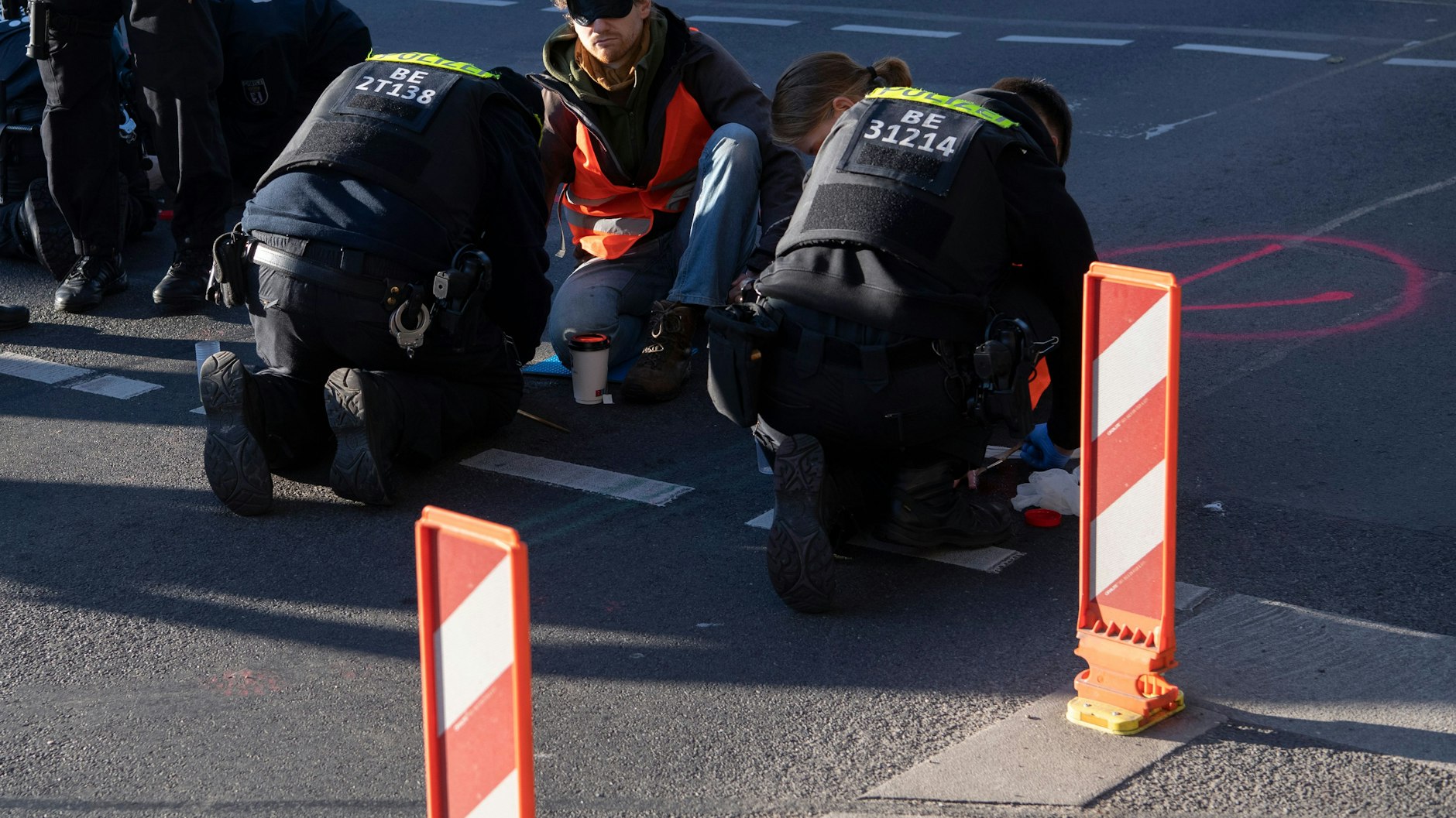 Polizisten müssten die festgeklebten Aktivisten vom Asphalt lösen.