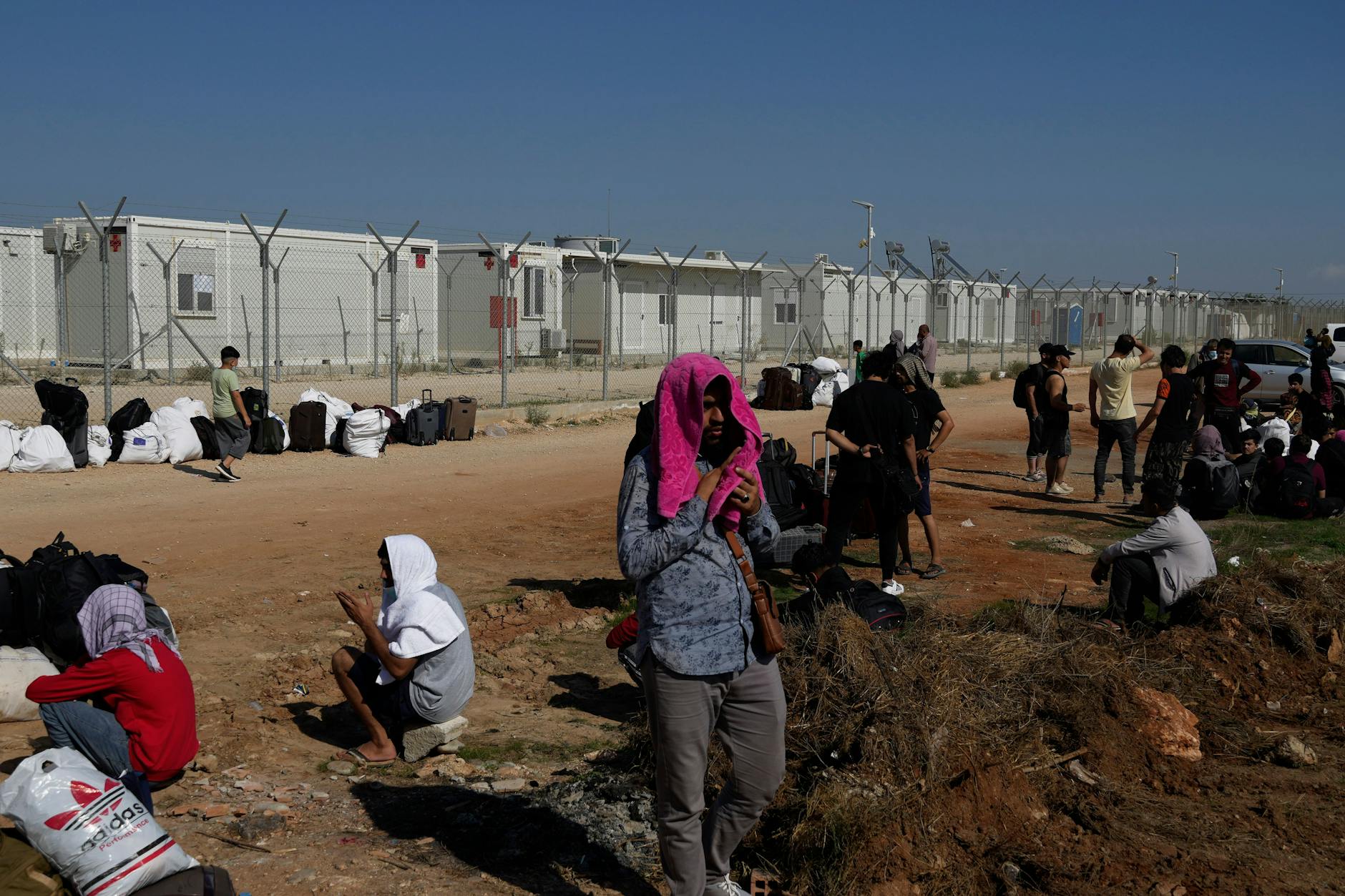 Migranten stehen und sitzen außerhalb des Aufnahmelagers von Pournara. Dort war es Freitag zu Ausschreitungen gekommen. 