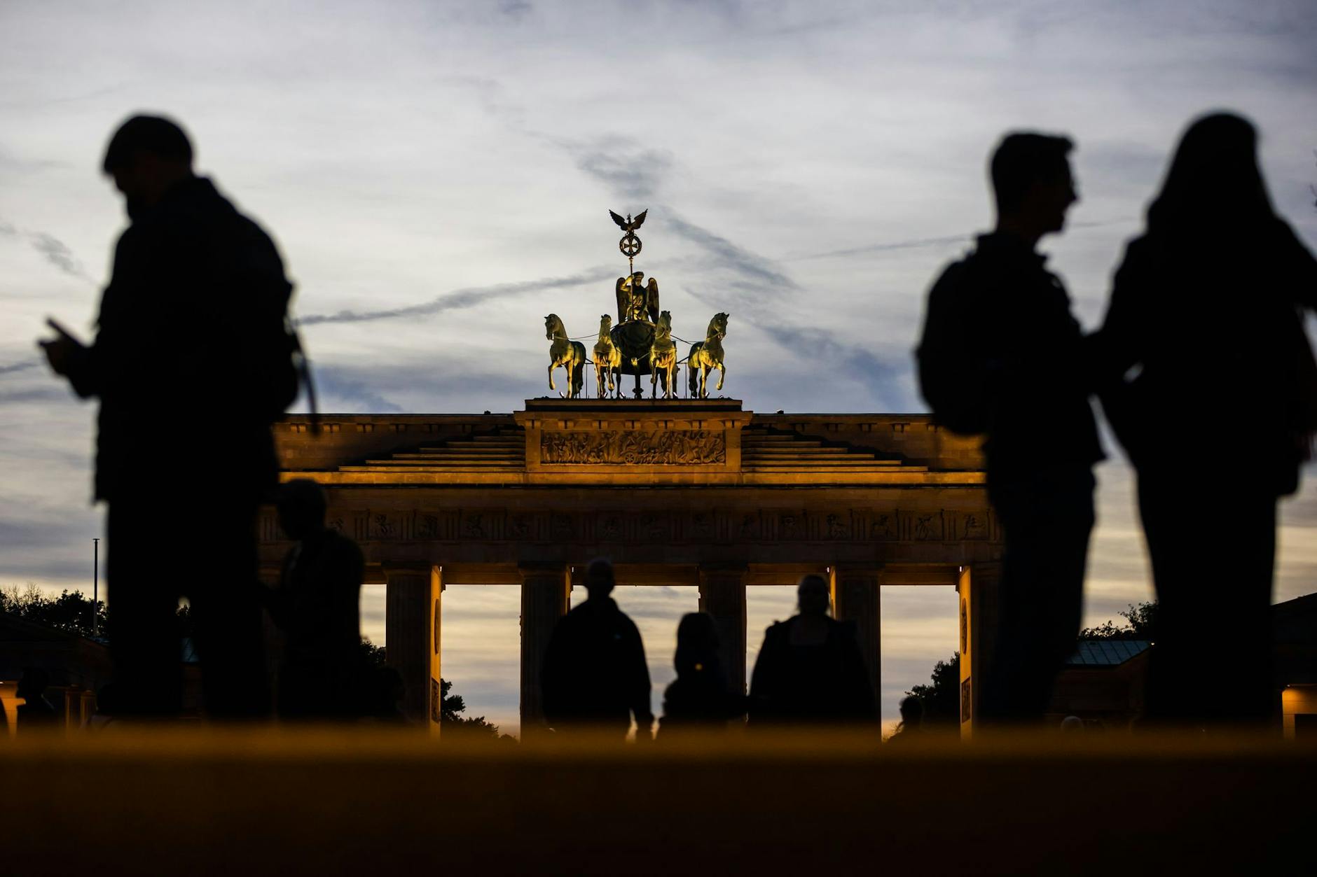 dpatopbilder - Besucher sind am Abend in Berlin am Brandenburger Tor unterwegs.