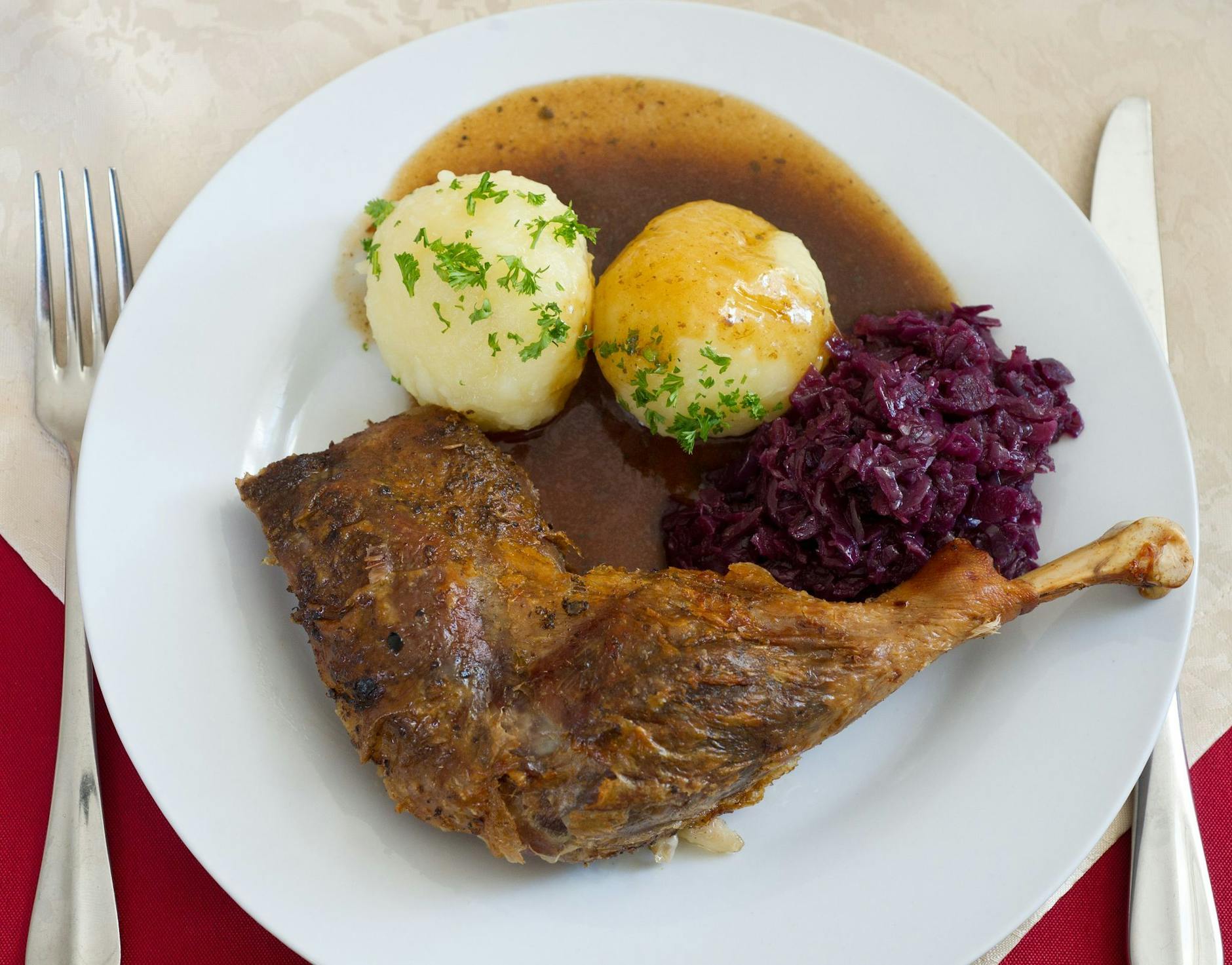 ARCHIV - Ein Teller mit Klößen, Rotkohl und einer Gänsekeule steht in einer Gaststätte in Brandenburg auf dem Tisch. a/Symbolbild