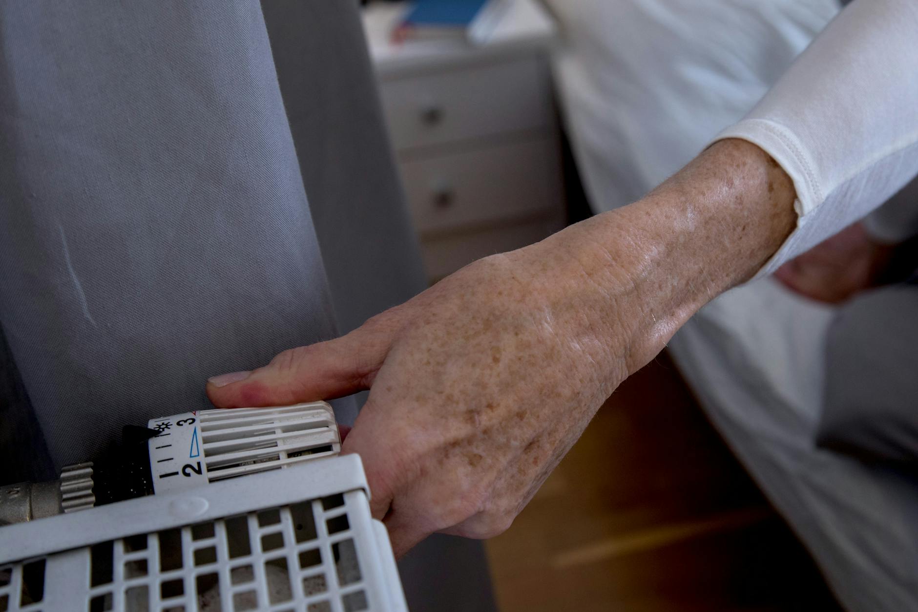 Eine Rentnerin dreht die Heizung auf. 