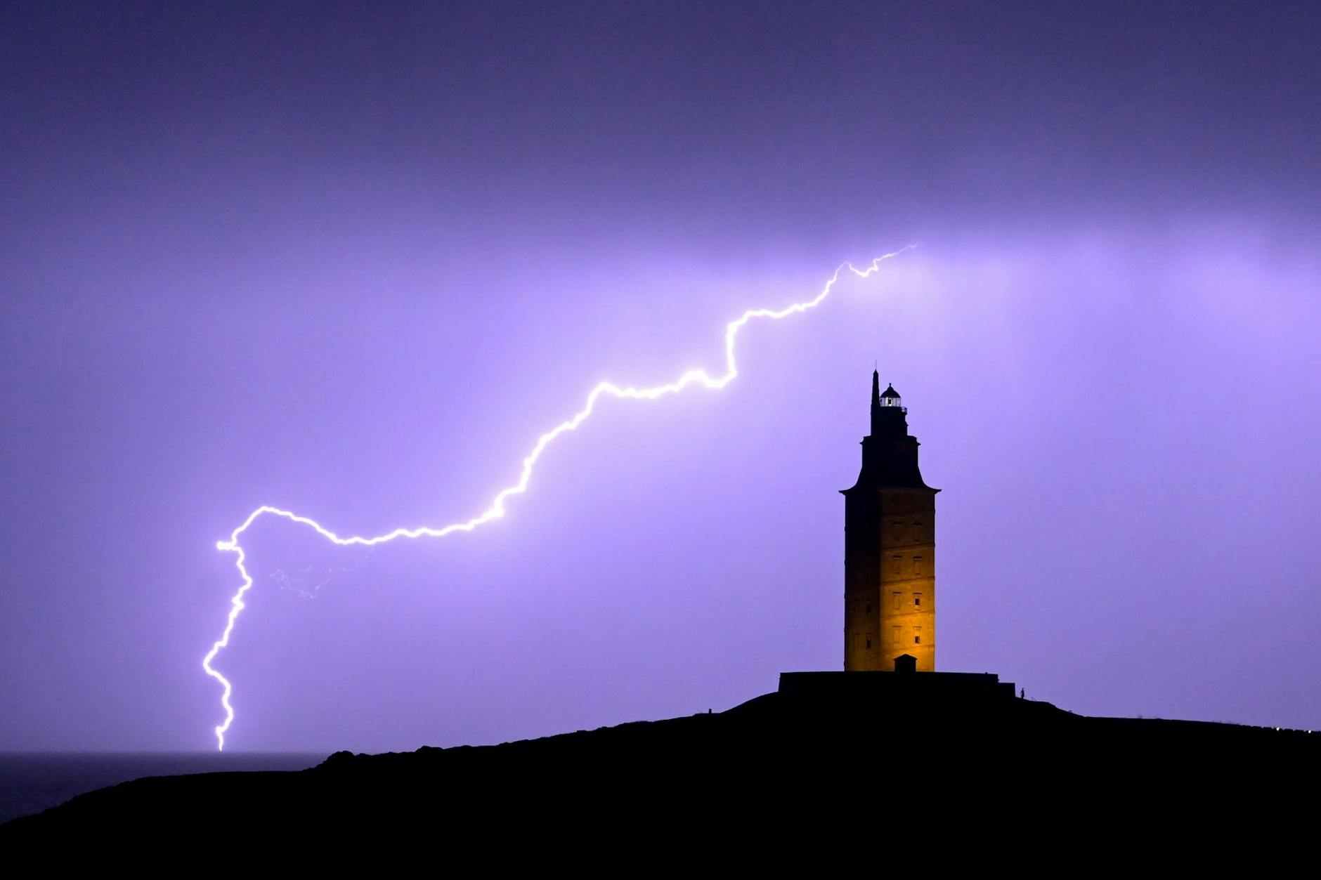 Ein Blitz erhellt den Himmel neben dem Herkulesturm in A Coruña. Dieser ist der älteste römische Leuchtturm der Welt.