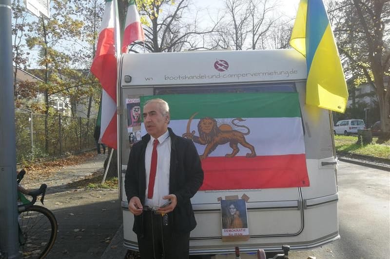 Nik Jafarzadeh vor der iranischen Botschaft. Der Wohnwagen hinter ihm war Ziel des Angriffs.