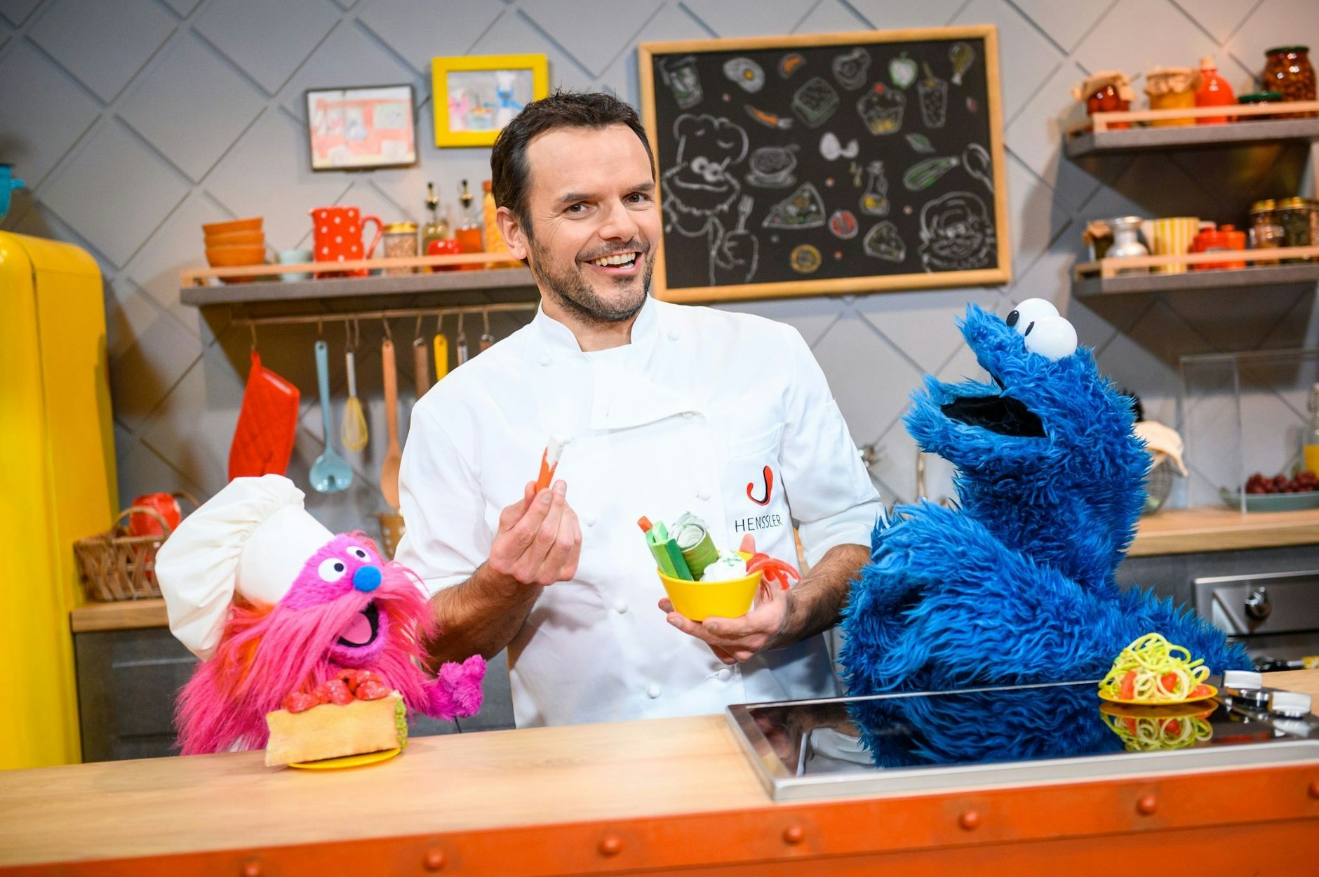 Der Fernsehkoch Steffen Henssler steht mit Gonger (l) unddem Krümelmonster im Studio.