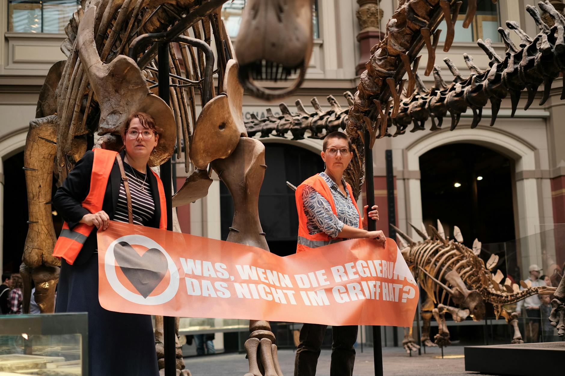 Protest der Klimaschutzaktivisten von der Letzten Generation im Naturkundemuseum Berlin. Die Frauen haben sich an einem Dinoskelett festgeklebt.