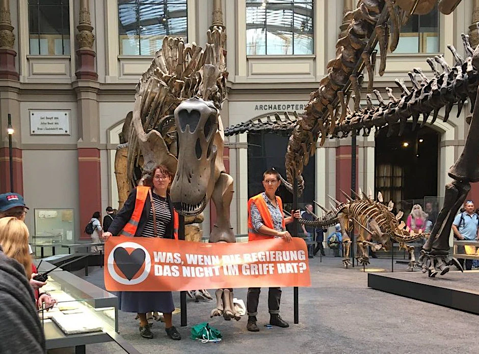 Zwei Frauen der „Letzten Generation“ haben sich an einem Dinosaurier-Skelett festgeklebt.&nbsp;