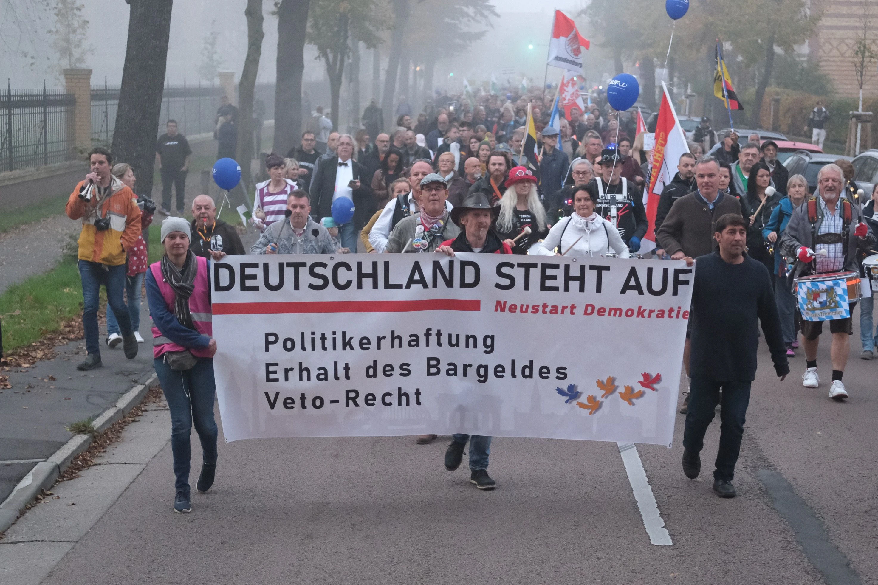 Lutherstadt Wittenberg: Teilnehmer einer Demonstration gehen mit einem Transparent und Fahnen eine Straße entlang.&nbsp;