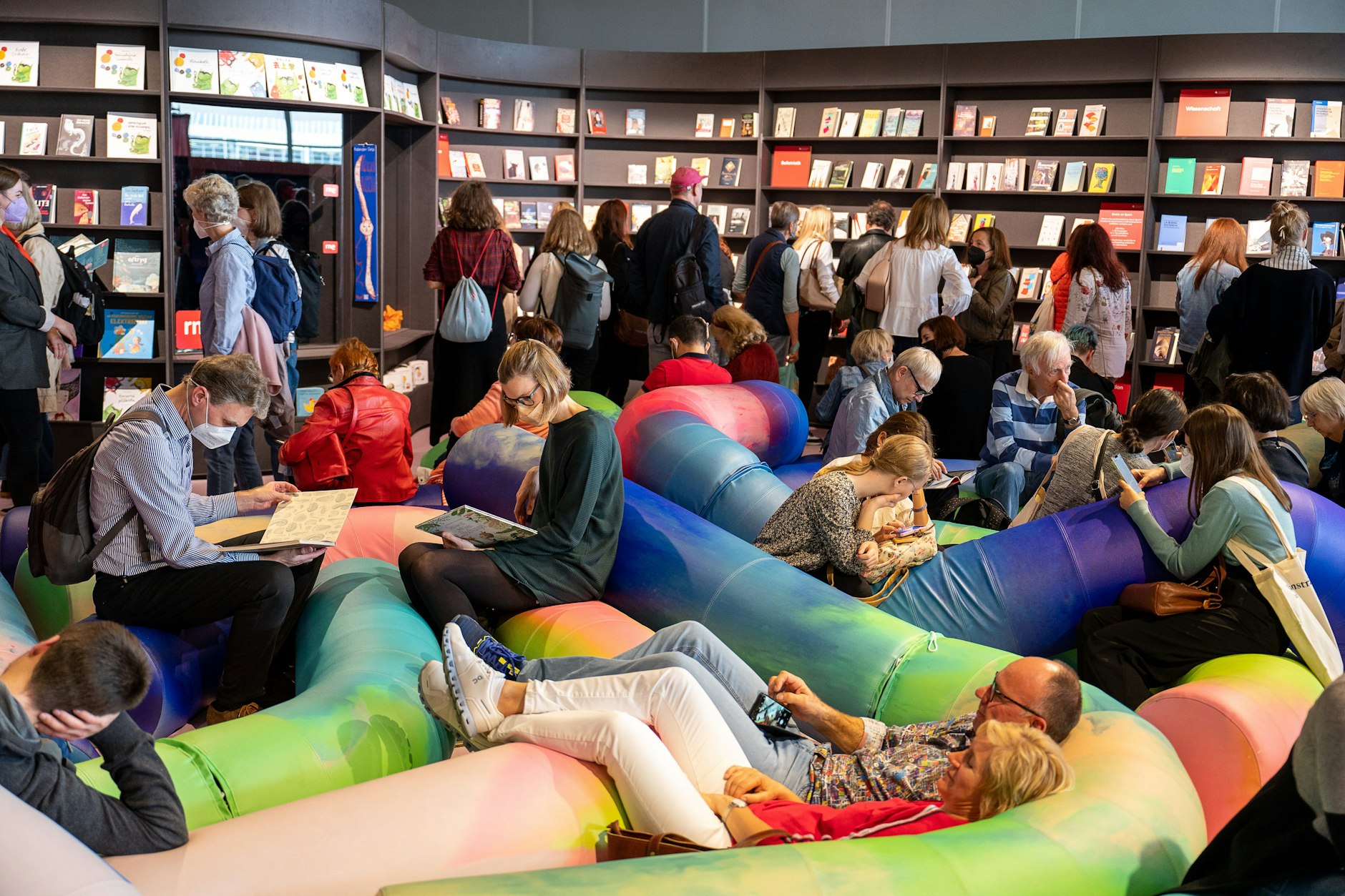 Besucher sitzen auf der Frankfurter Buchmesse im Pavilion des Gastlandes Spanien vor einer Bücherwand. 