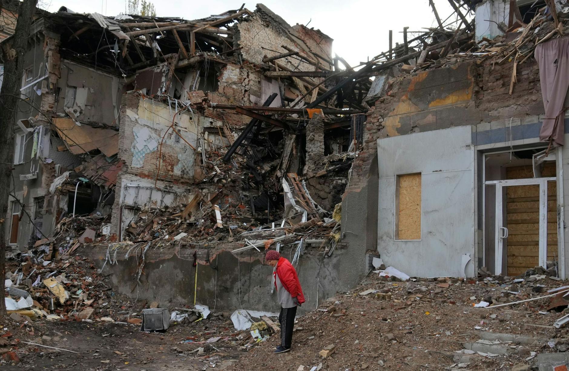 Eine Frau steht in der Nähe ihres Hauses, das durch Beschuss vor einem Monat zerstört wurde.