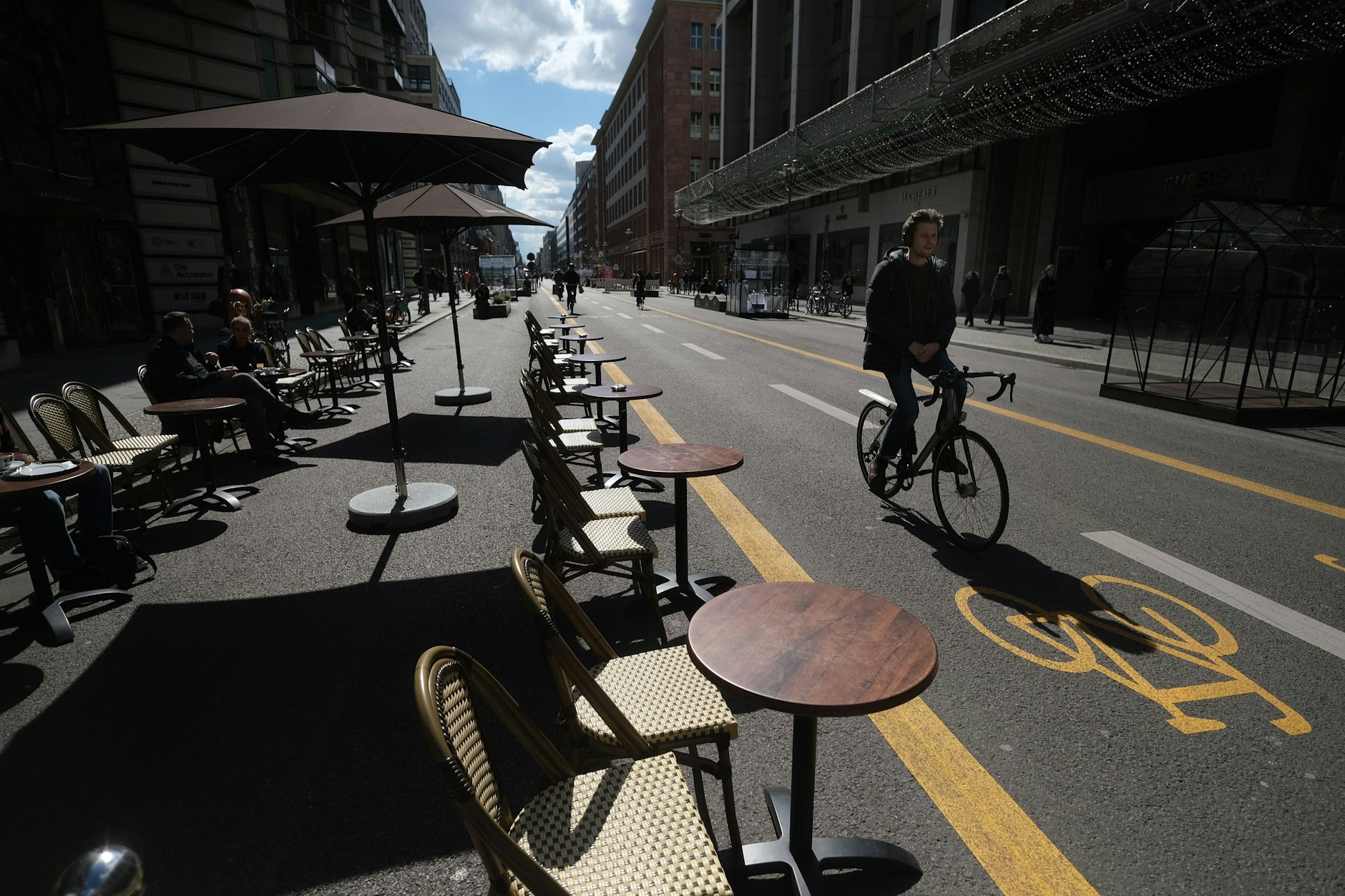 Die autofreie Friedrichstraße in Mitte: Sitzgelegenheiten und Cafétische stehen auf der früheren Fahrbahn. In der Mitte verläuft ein provisorischer Radfahrstreifen. Er wird 2023 verschwinden.
