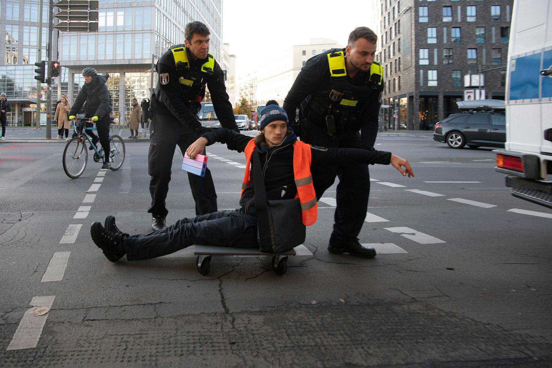 Ein Aktivist der Letzten Generation wird von Beamten der Polizei von der Straße entfernt.