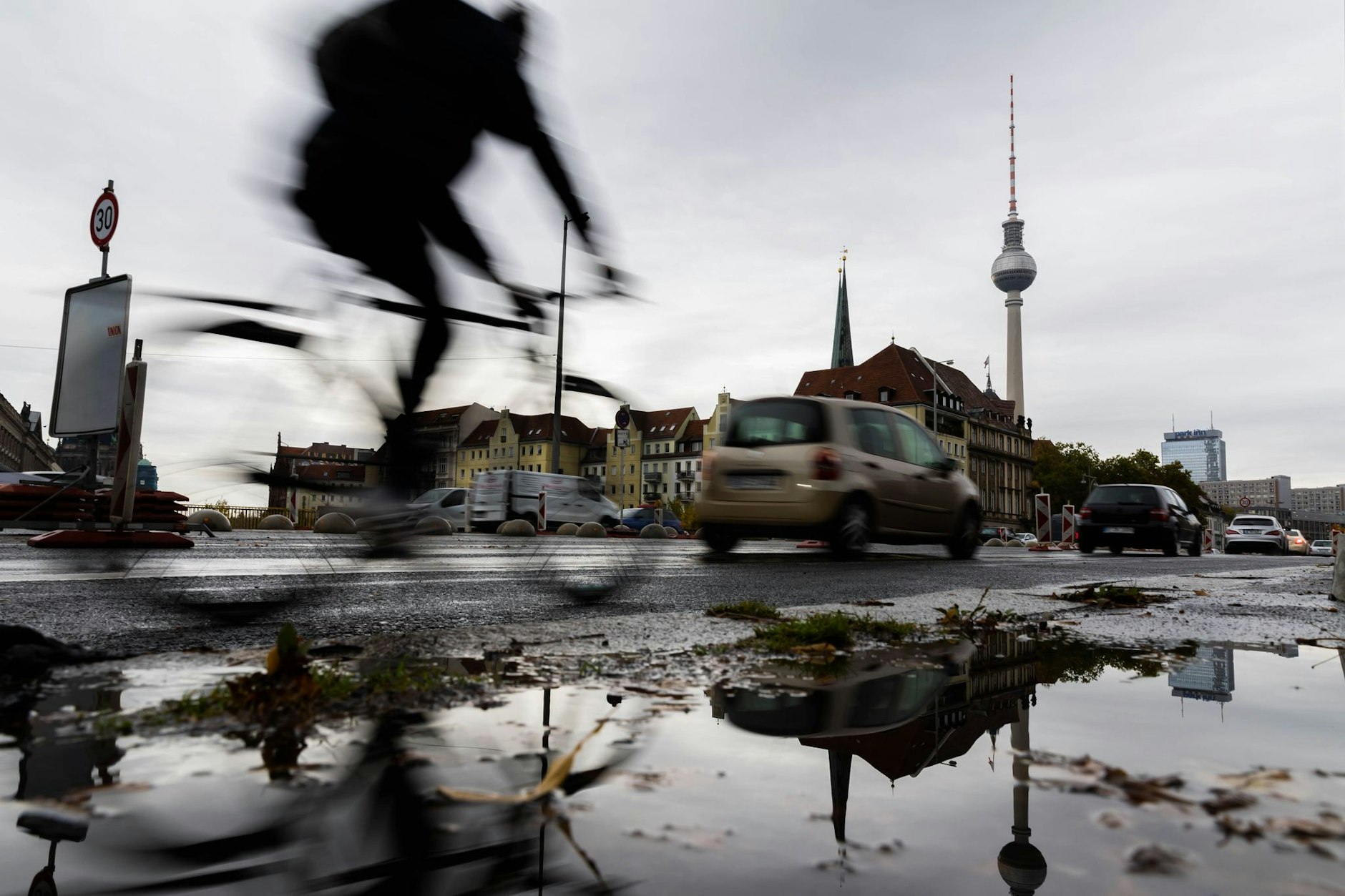 Bei nasskaltem Wetter fährt ein Fahrradfahrer vor dem Berliner Fernsehturm über die Mühlendammbrücke. Das Wetter in den kommenden Tagen wird ungemütlicher.