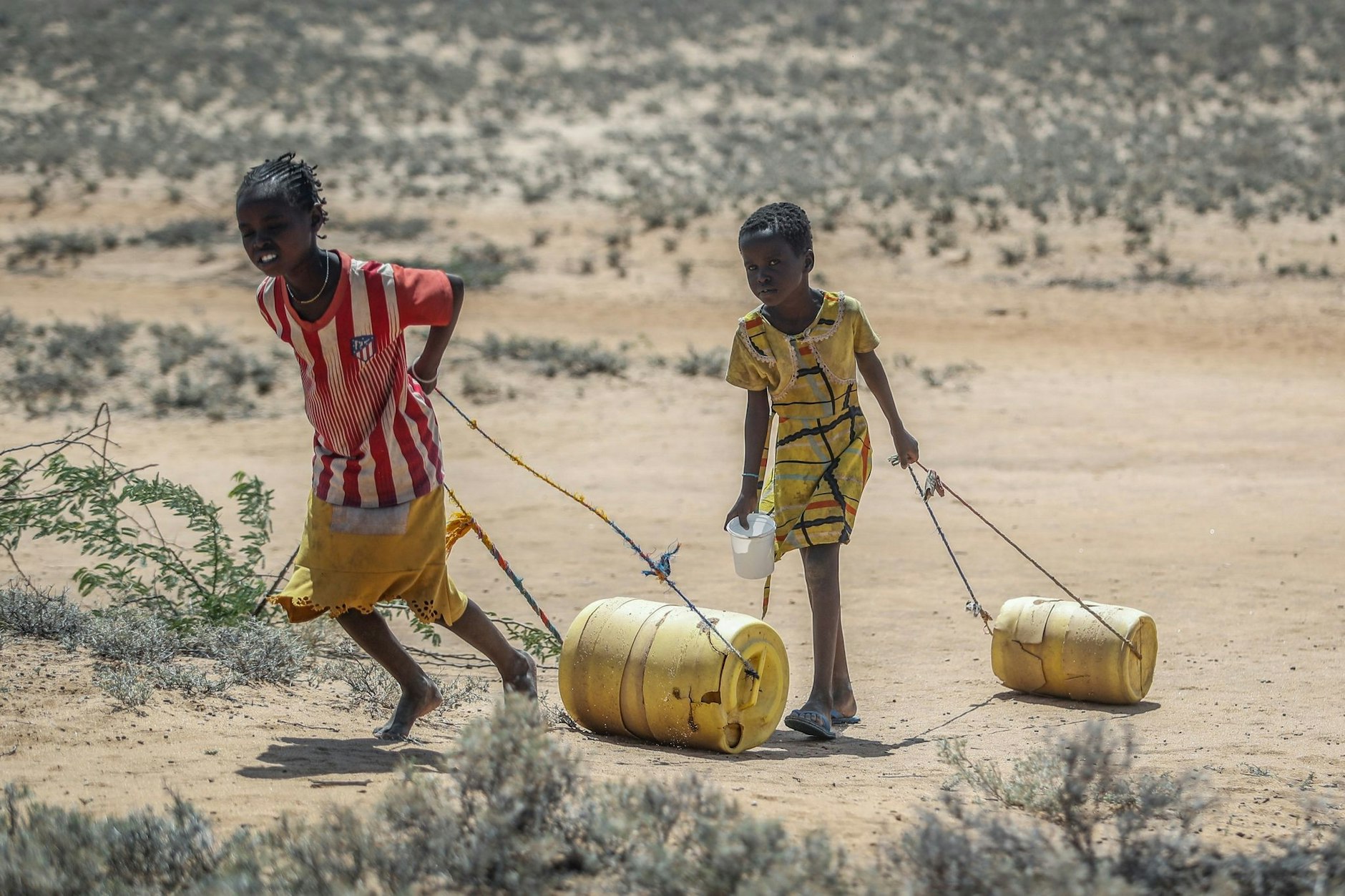 Unterernährte Kinder in Kenia ziehen Wasserkanister durch die knochentrockene Wüste Kenias: Der Klimawandel ist Realität.