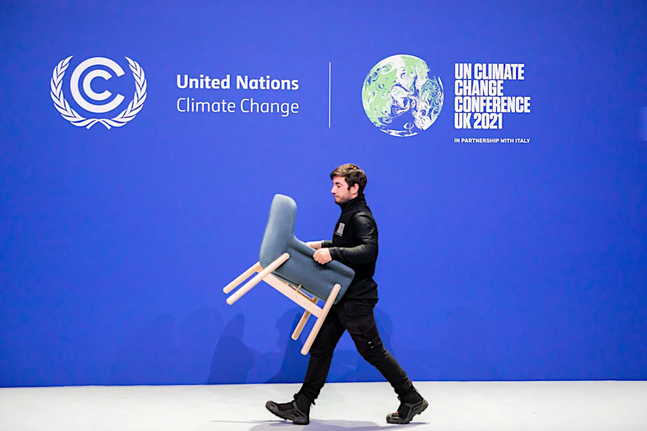 ARCHIV - Ein Mitarbeiter trägt bei der UN-Klimakonferenz COP26 einen Stuhl von einer Bühne.  