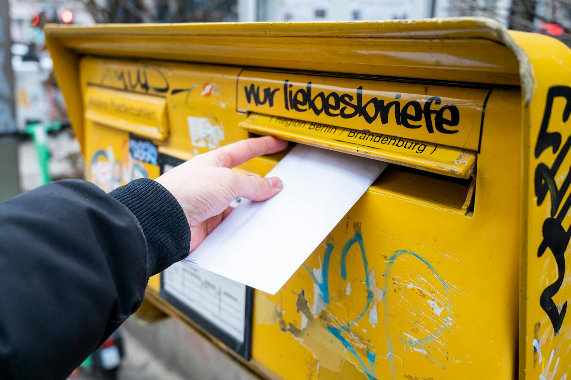 Ein Mann wirft einen Brief in einen Briefkasten. Die Post erwägt eine Zwei-Klassen-Gesellschaft für Briefe.