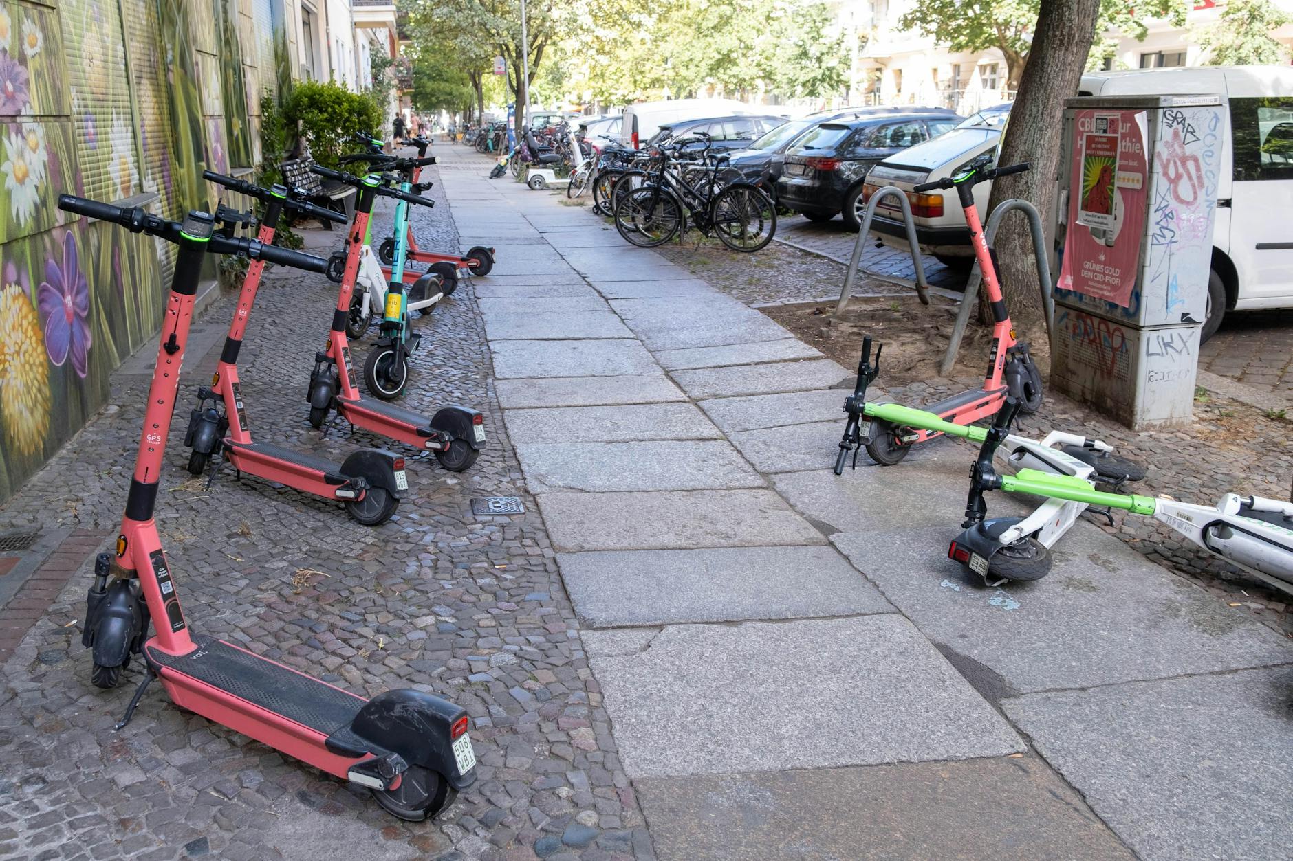 Wahllos abgestellte E-Scooter in Berlin. Auch lachsrosa Fahrzeuge von Voi gehören dazu.