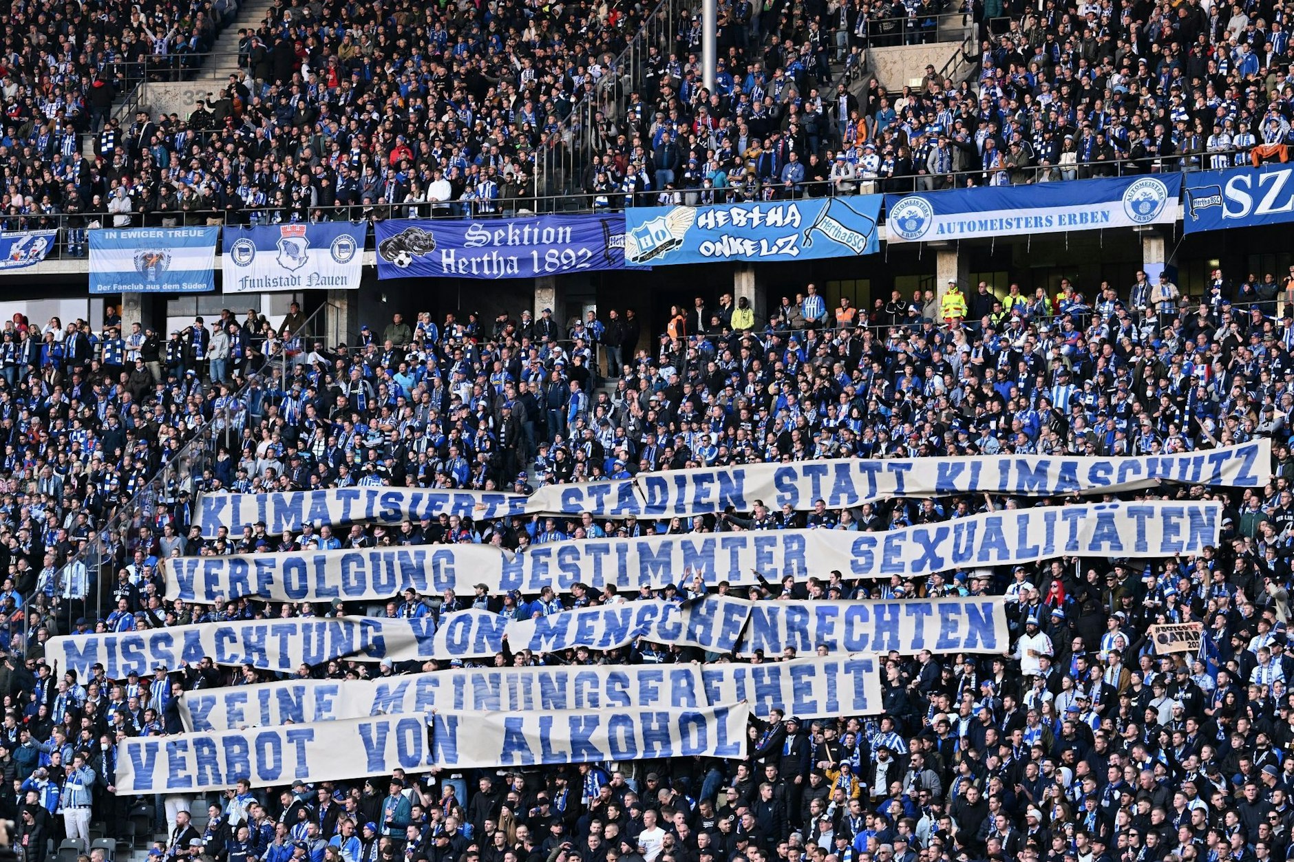 Hertha-Fans in der Ostkurve zeigen Spruchbänder gegen die bevorstehende Fußballweltmeisterschaft in Katar.