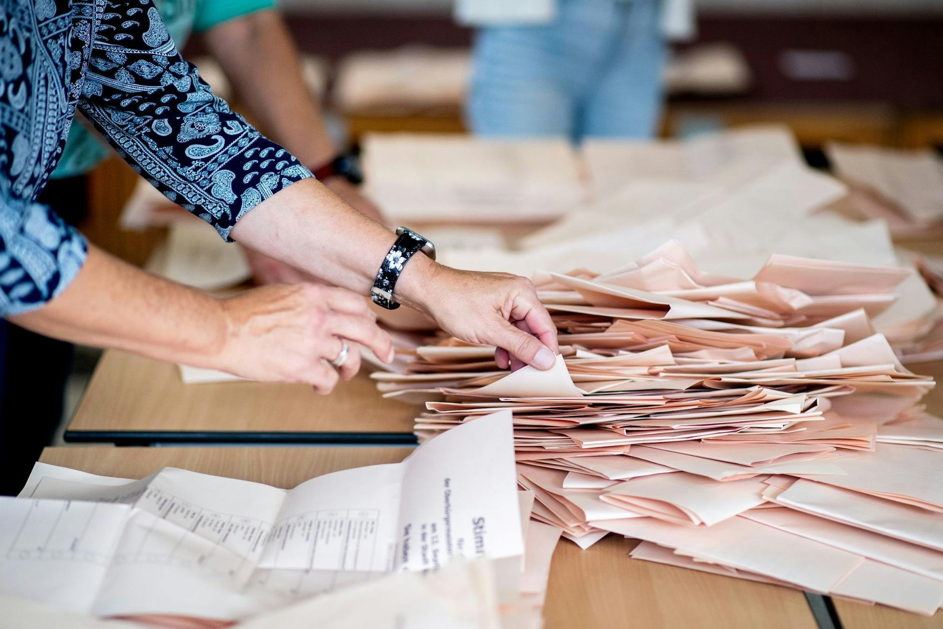 Eine Wahlhelferin sortiert in einem Wahllokal die Stimmzettel für die Auszählung. 