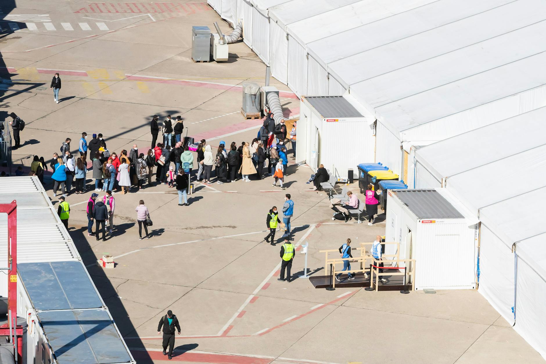 Menschen stehen im Berliner Ankunftszentrum für Geflüchtete aus der Ukraine am ehemaligen Flughafen Tegel vor einem Zelt Schlange.