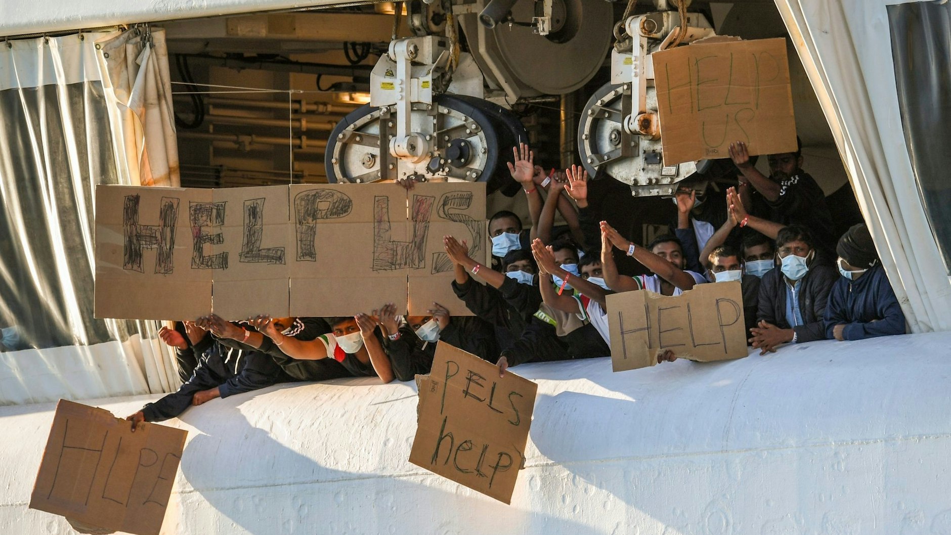 An Bord der "Geo Barents" halten Menschen Transparente hoch. Die italienischen Behörden lassen sie nicht an Land.