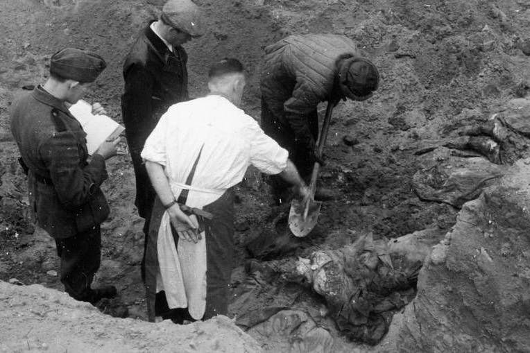 Das Massaker von Katyn, 1940: Ein Mitglied der Internationalen Medizinischen Kommission gibt einem Arbeiter, der die Leichen der polnischen Offiziere ausgräbt, Anweisungen.