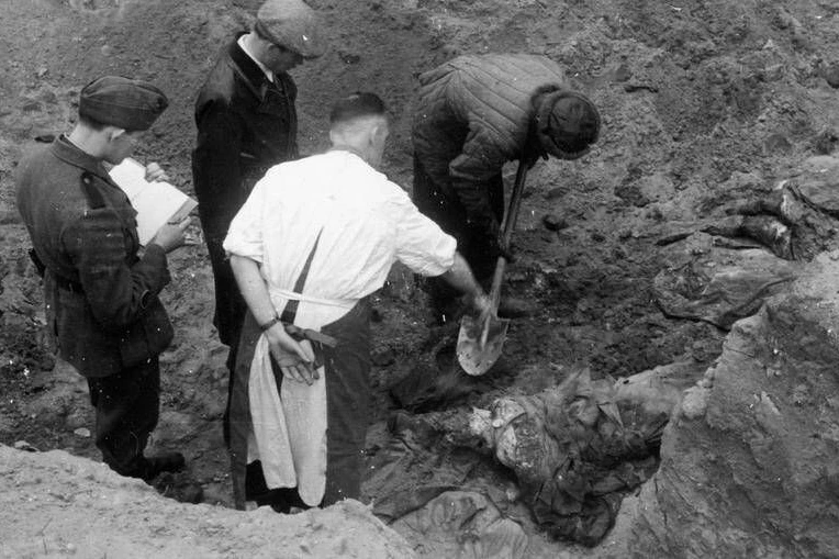 Das Massaker von Katyn, 1940: Ein Mitglied der Internationalen Medizinischen Kommission gibt einem Arbeiter, der die Leichen der polnischen Offiziere ausgräbt, Anweisungen.