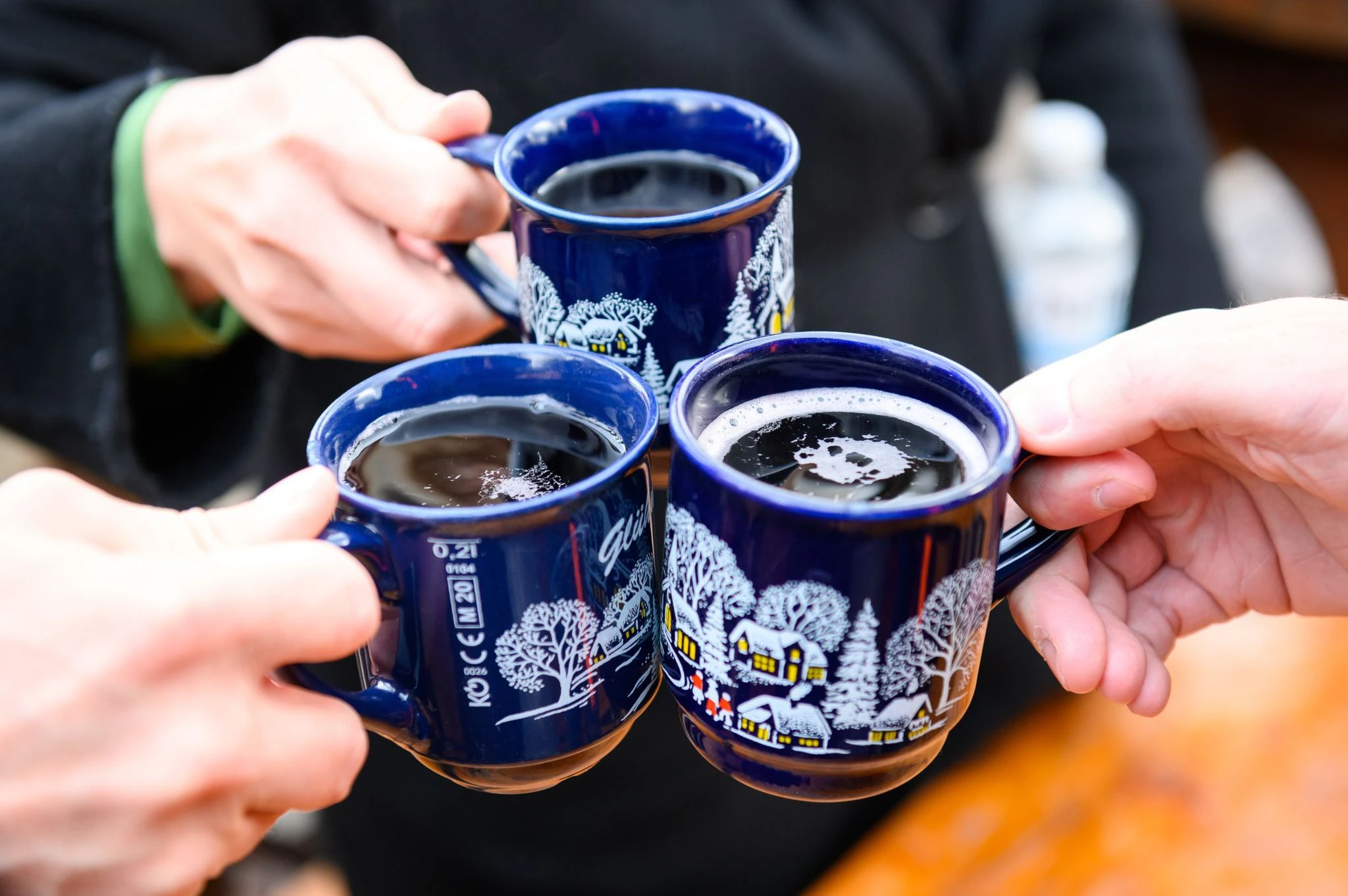 dpatopbilder - Drei Besucher stoßen in Hamburg mit Glühwein an.  