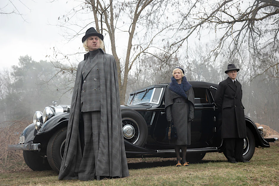 Cape und damals hochmodische „Elephant pants“: Lars Edinger als Alfred Nyssen in der 4. Staffel „Babylon Berlin“. Hinten Hannah Herzsprung als seine ebenfalls erblondete Frau und Holger Handtke als Anwalt Wegner.