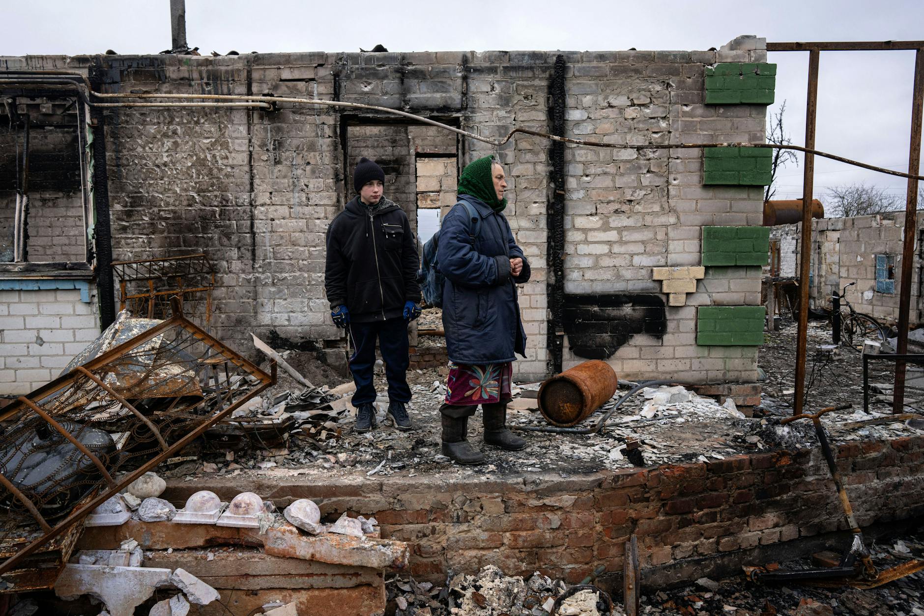 FILE - Danyk Rak, 12, stands with his grandmother Nina on the debris of their house destroyed by Russian forces' shelling in the village of Novoselivka, near Chernihiv, Ukraine, April 13, 2022. Danyk's family home was destroyed and his mother seriously wounded as Russian forces bombarded Kyiv’s suburbs and surrounding towns in a failed effort to seize the capital. (AP Photo/Evgeniy Maloletka, File)