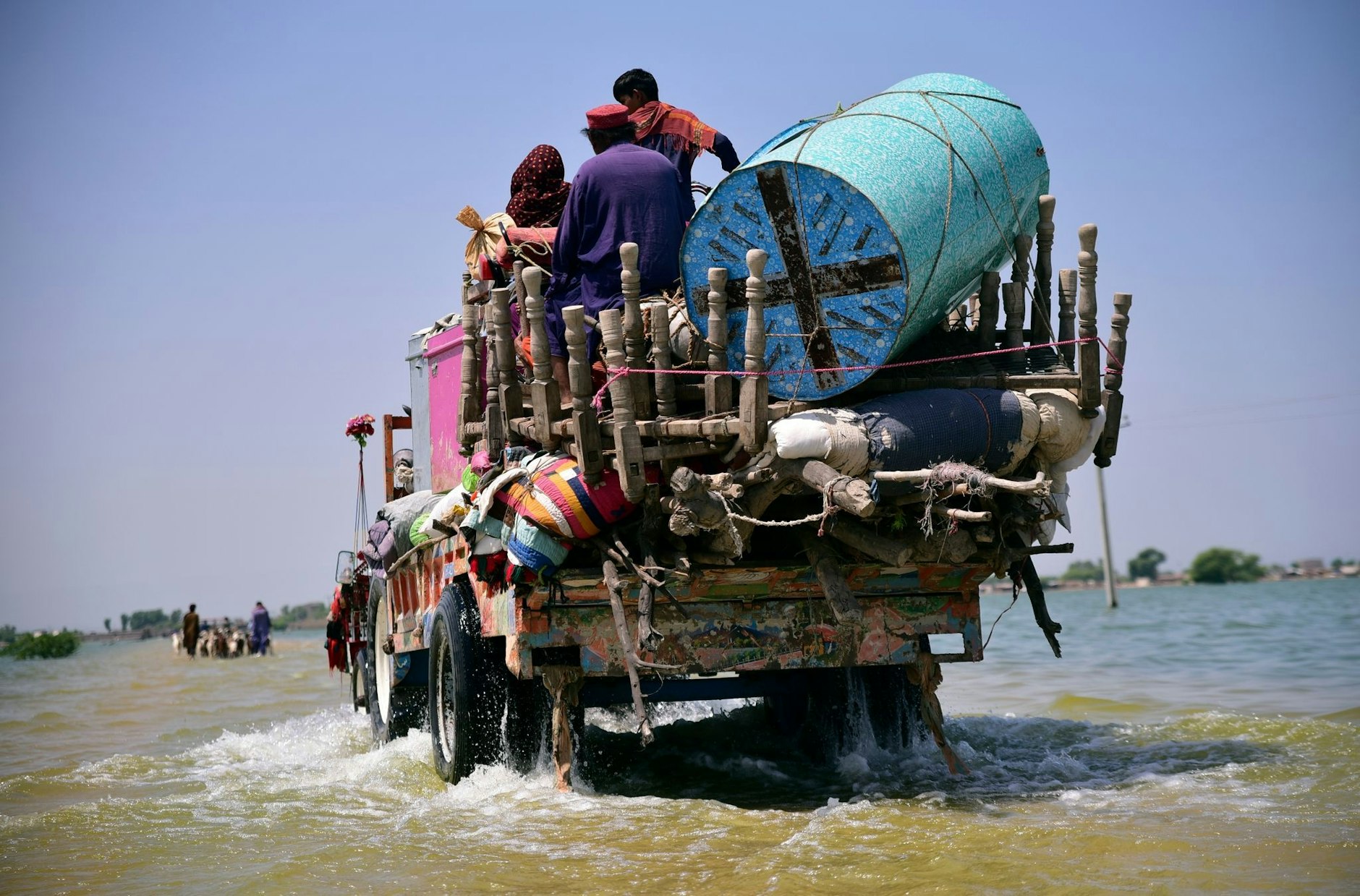 ARCHIV - Opfer von Überschwemmungen durch Monsunregen tragen Habseligkeiten aus ihrem überfluteten Haus in der Provinz Sindh.  
