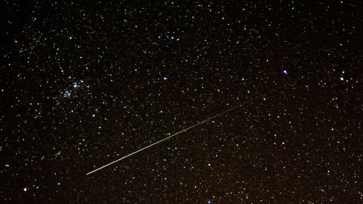 Eine Sternschnuppe leuchtet am Nachthimmel.