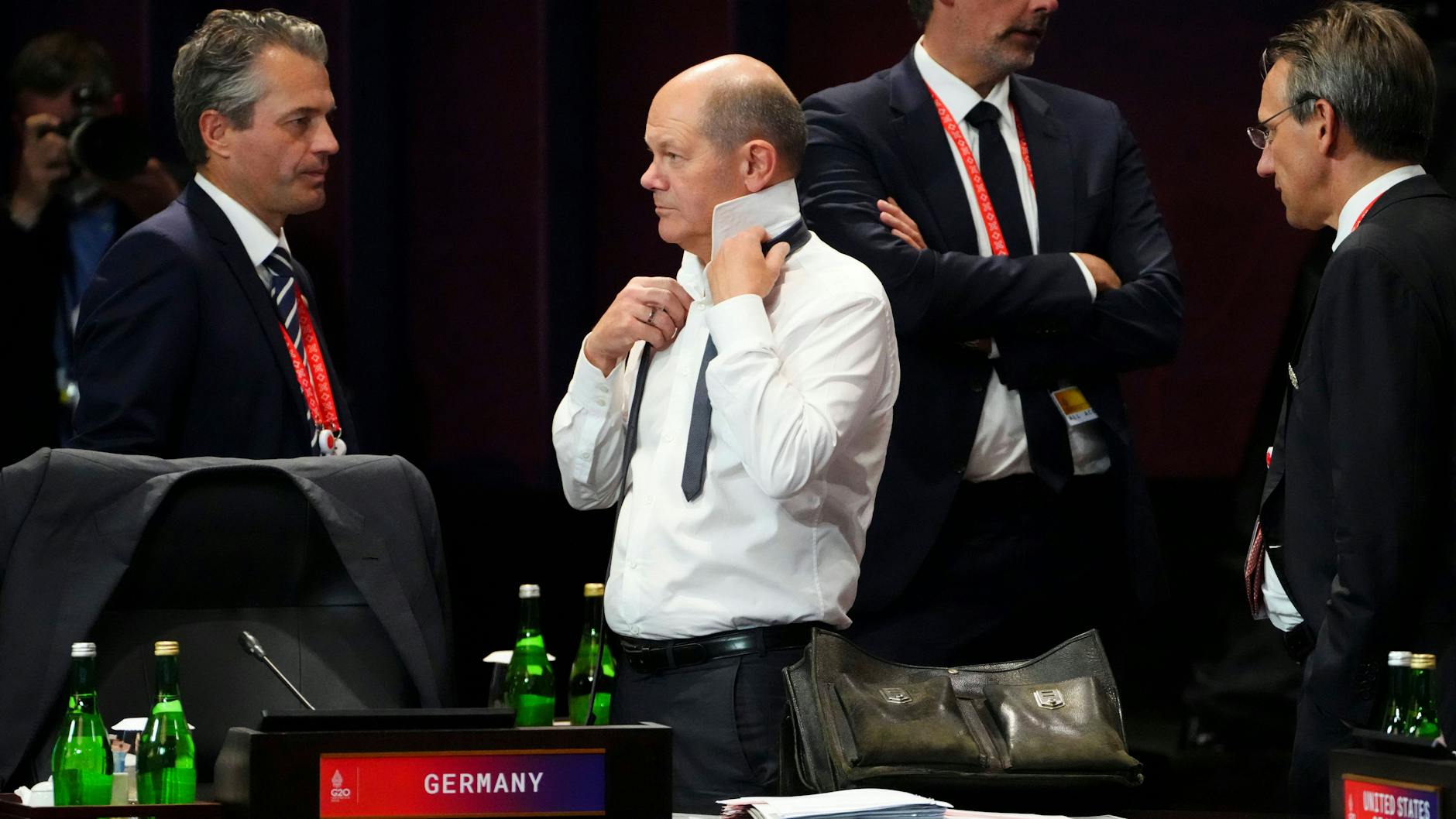 Bundeskanzler Olaf Scholz (SPD) bindet im Tagungsraum der G20 seinen Schlips.