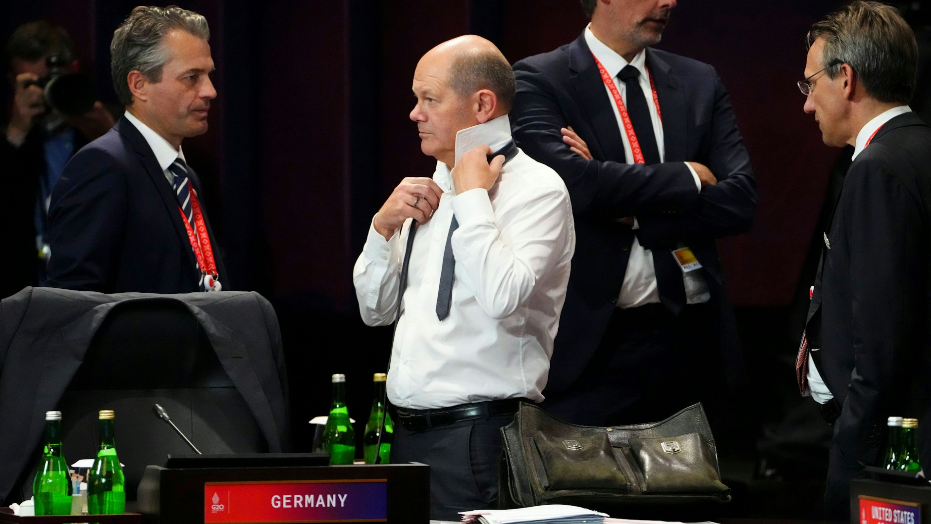 Bundeskanzler Olaf Scholz (SPD) bindet im Tagungsraum der G20 seinen Schlips.