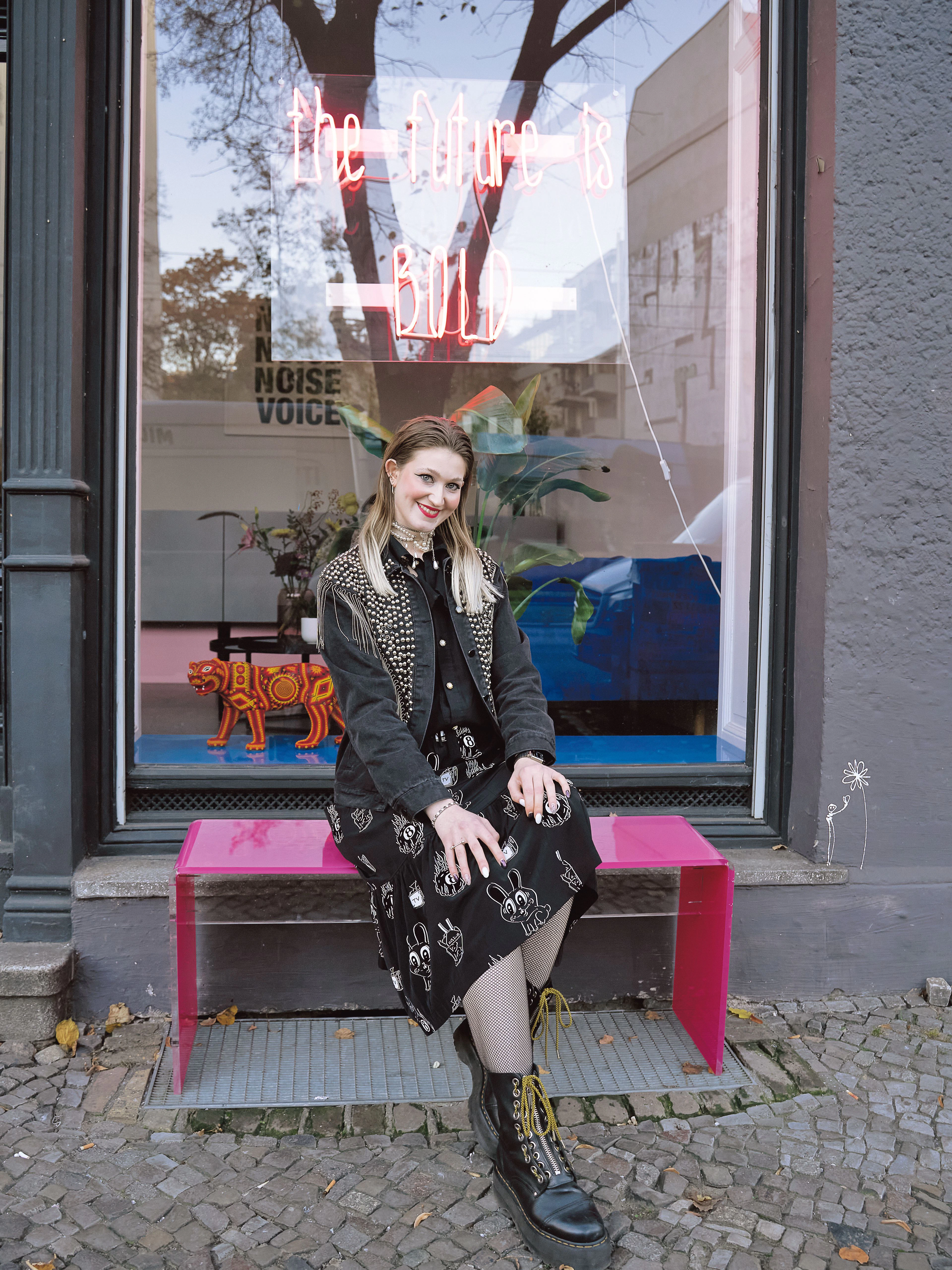 Adriana arbeitet in der PR-Agentur Bold „als Mädchen für alles“, wie sie heiter erläutert. Die opulente Jacke aus dem Nürnberger Modehaus Jovi Fashion kombiniert sie mit einer Vintage-Bluse von Humana und einem Alexander-McQueen-Rock, den sie bei Vinted für 60 Euro geschossen hat. Die Boots sind von Dr. Martens.&nbsp;
